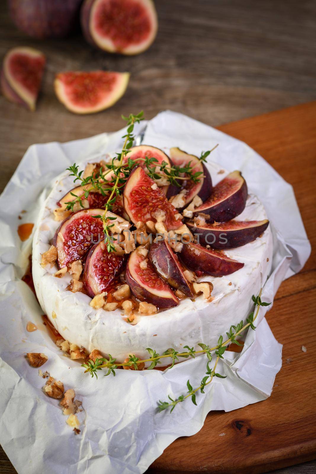 Brie cheese served on a wooden board with figs, walnuts and honey