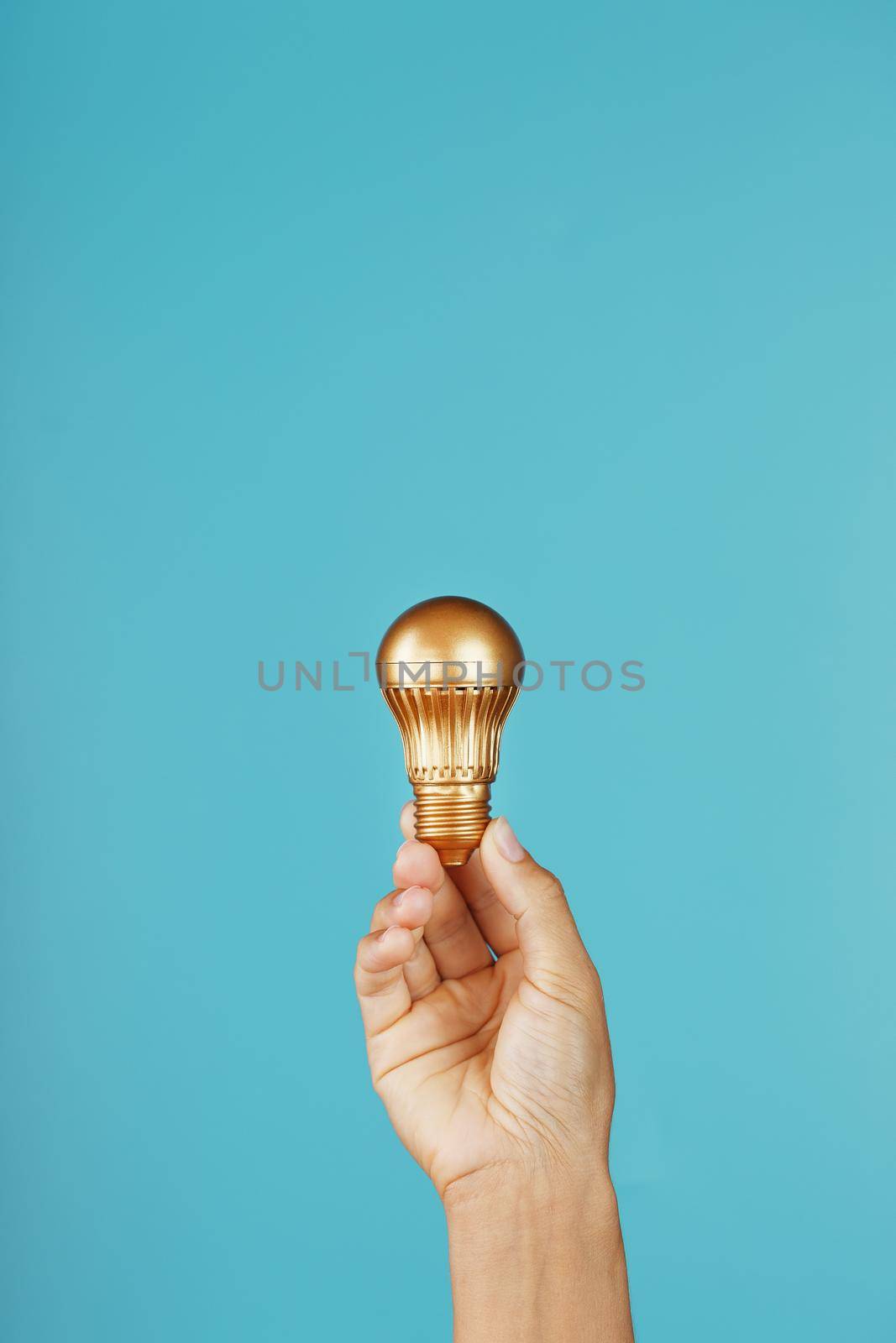 Gold light bulb in hand on a blue background, as a concept of ideas and assistance by AlexGrec
