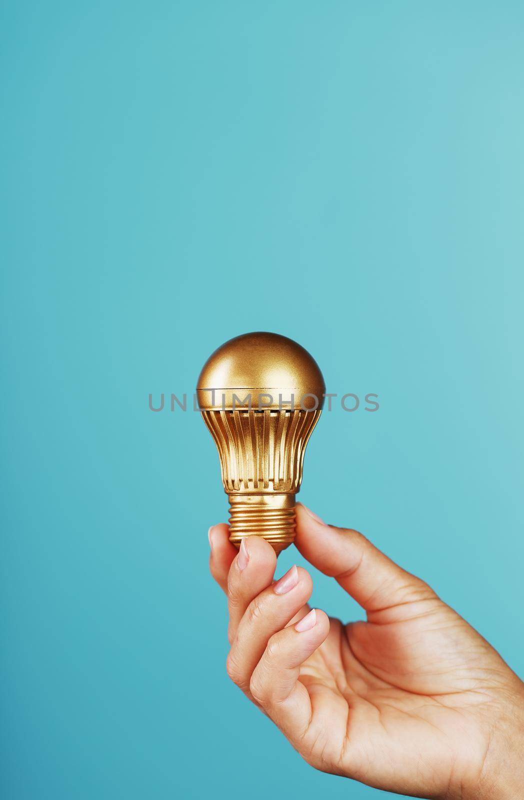 Gold light bulb in hand on a blue background, as a concept of ideas and assistance. Isolate, minimalistic