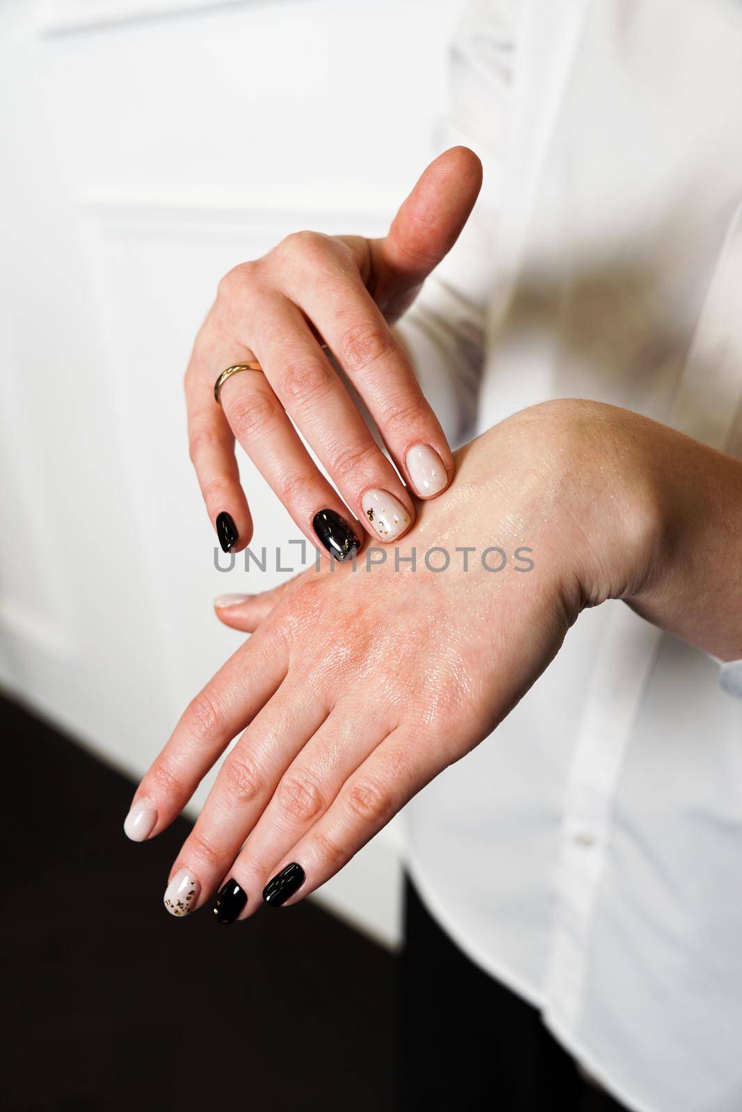 Close up - young woman applying moisturizing nourishing oil for hands. Organic beauty cosmetics natural oil product advertisement. Vertical photo