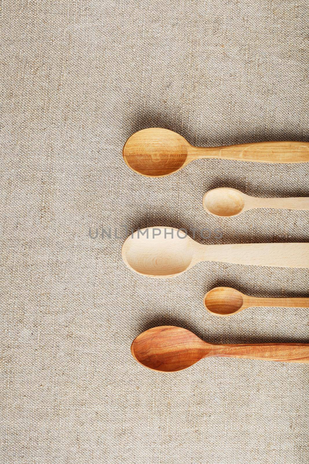 Natural wood spoons in a row on burlap fabric. Natural natural materials. Caring for the environment
