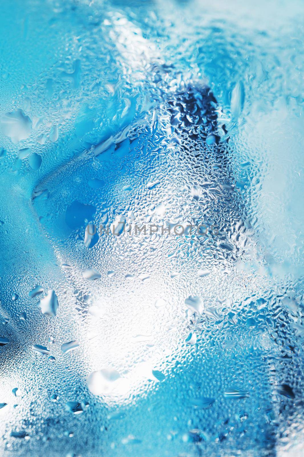 Glass with water and ice cubes on a blue background by AlexGrec