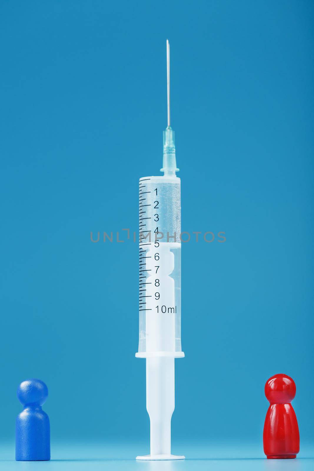 A miniature of a blue and red man between a syringe with a vaccine. The concept of the conflict of vaccination and anti-vaccination. Pros and cons of medical drugs