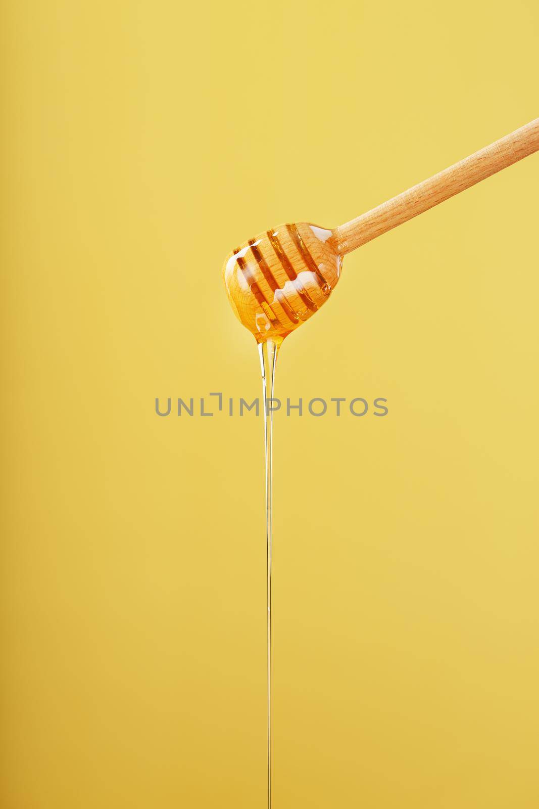 Natural Honey flows down from a honey bucket on a yellow background. by AlexGrec