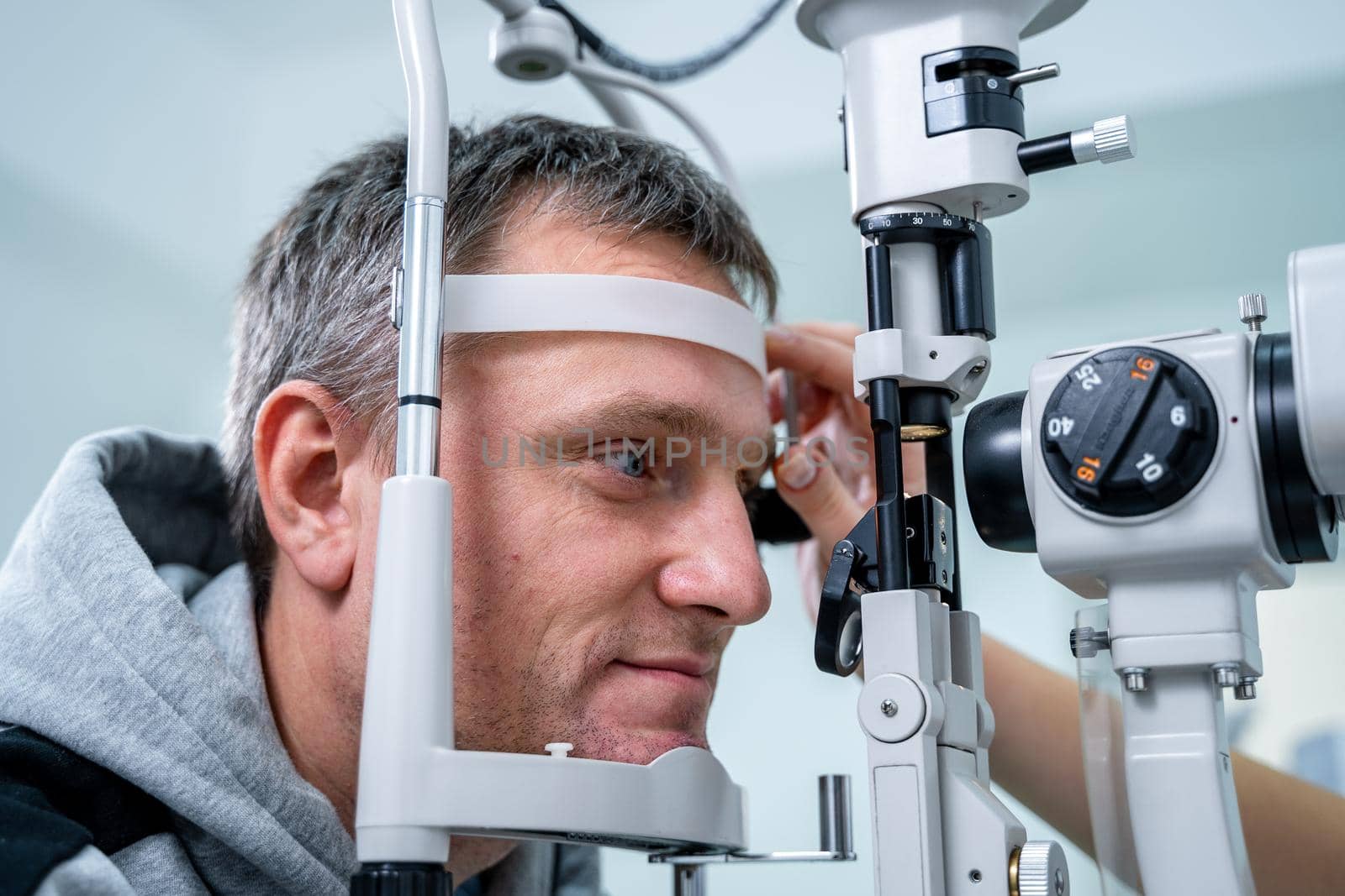 Ophthalmologist and patient testing eyesight. Man doing eye test with optometrist. Ophthalmologist using apparatus for eye examination in clinic. Doctor examining patient doing eyesight measurement.