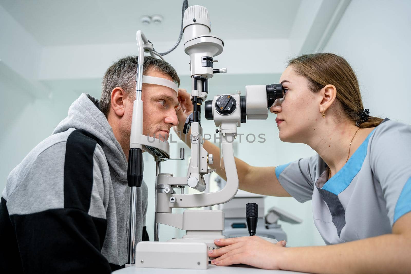 Doctor and patient in ophthalmology clinic. Male patient checking vision with special eye equipment. Optometry concept. Man visiting optician. Patient at slit lamp of optician or optometrist by Tomashevska