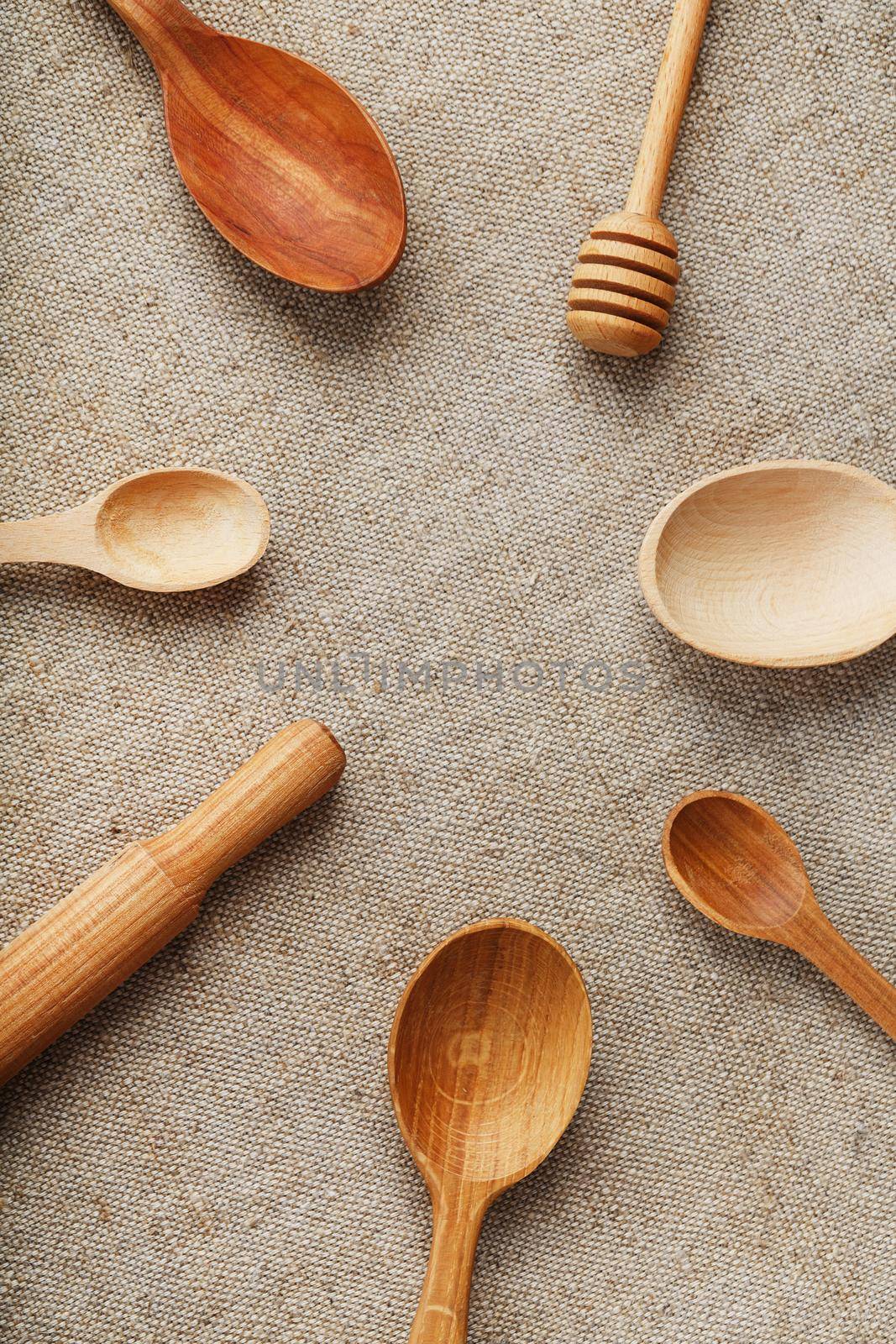 Natural wood spoons in a row on burlap fabric. Natural natural materials. by AlexGrec