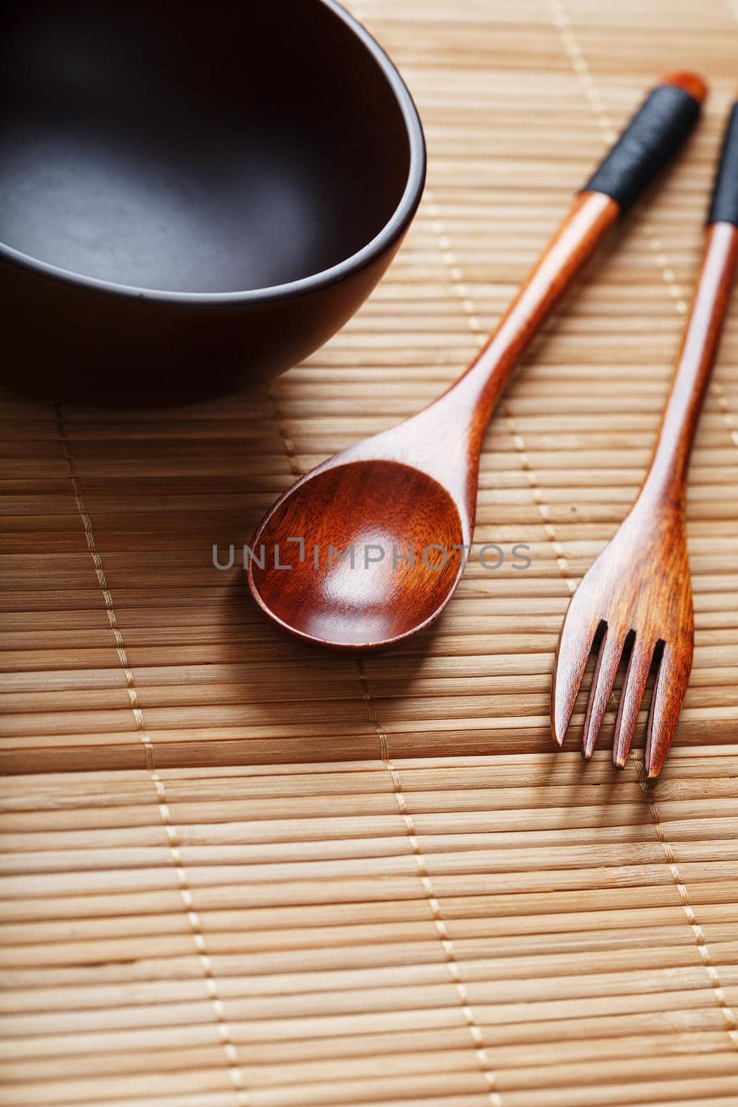Natural wood plate, spoon and fork on a bamboo backing. Asian food handicraft concept. View from above