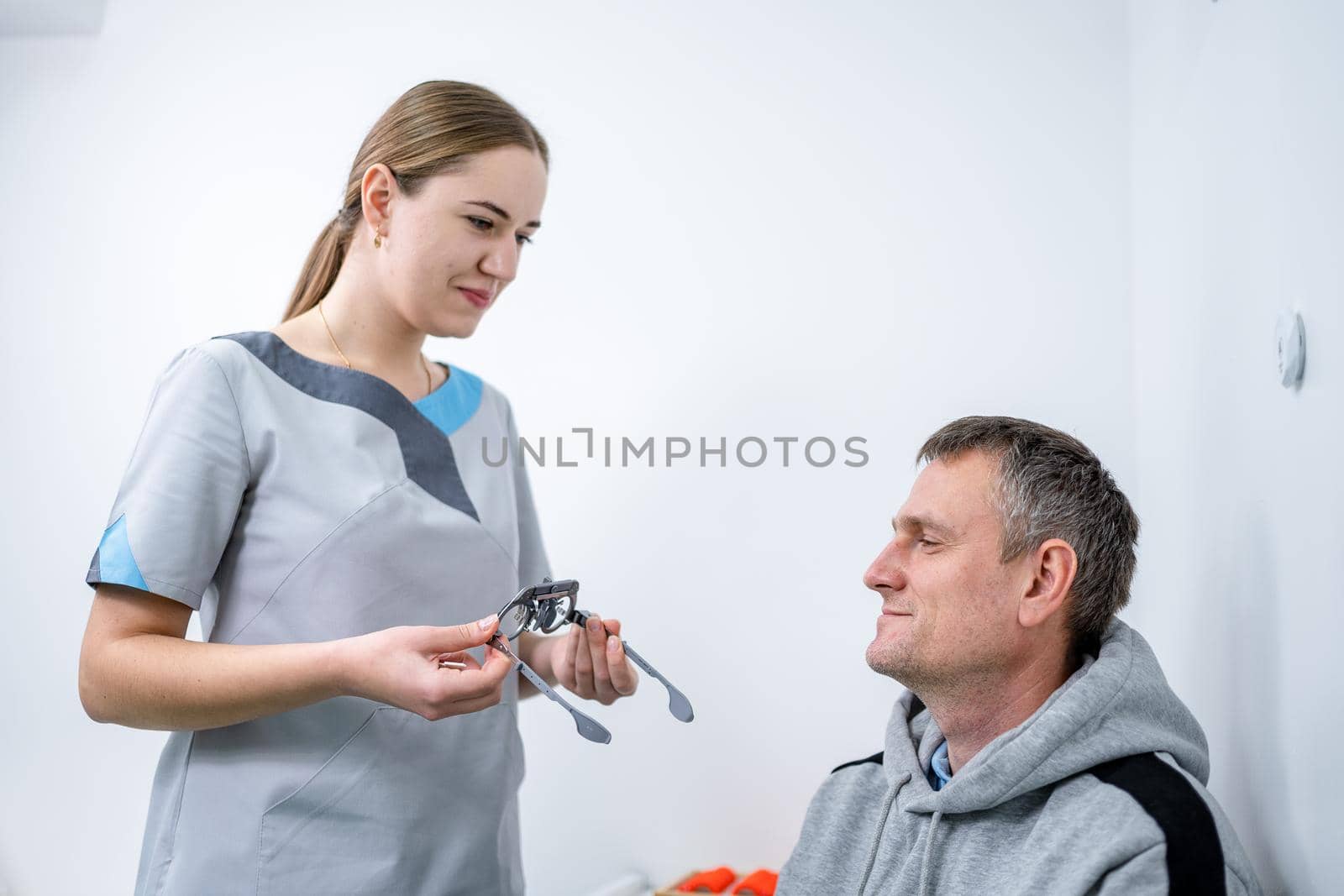 Male patient undergoes an eye test and prescription for eyeglasses in ophthalmology clinic. Optometrist checking patient eyesight and vision correction. Changing lenses on trial frame on patient nose.