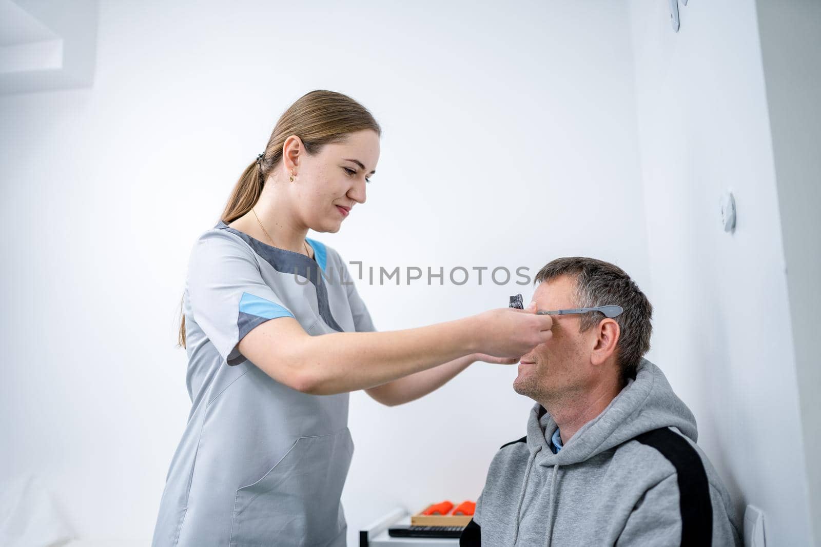 Examining patient vision. Eye exam. Optometrist checking patient eyesight and vision correction. Patient undergoing vision check with special ophthalmic glasses at eye clinic. Selection of eyeglasses by Tomashevska
