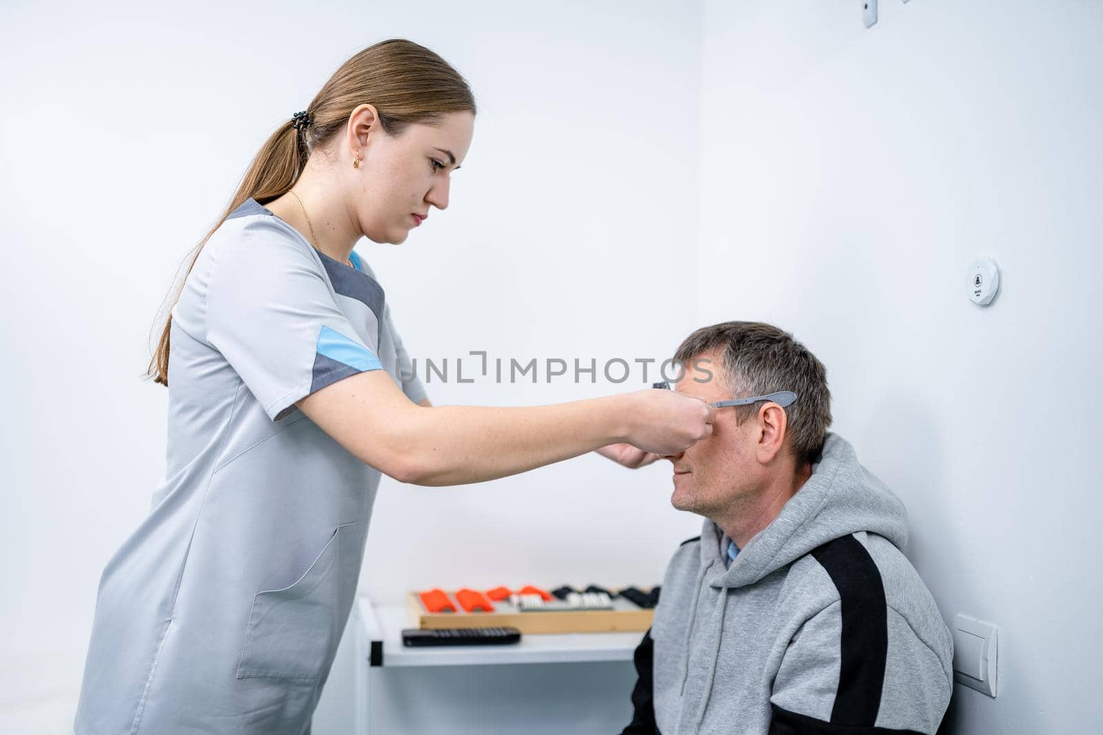 Male patient undergoes an eye test and prescription for eyeglasses in ophthalmology clinic. Optometrist checking patient eyesight and vision correction. Changing lenses on trial frame on patient nose by Tomashevska