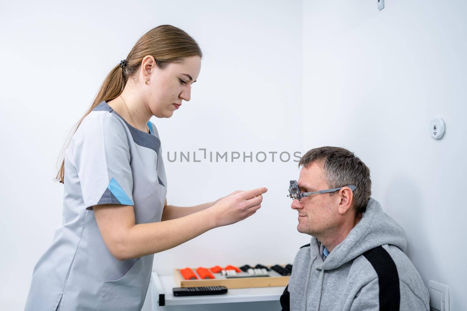 Examining patient vision. Eye exam. Optometrist checking patient eyesight and vision correction. Patient undergoing vision check with special ophthalmic glasses at eye clinic. Selection of eyeglasses.