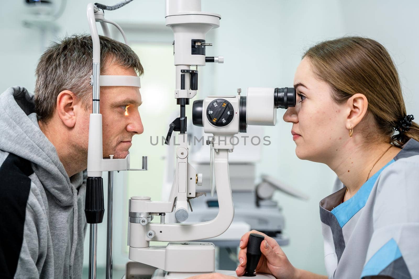 Optometrist examining the eyes of a male patient in a modern ophthalmology clinic. Eye doctor with man patient during an examination in modern clinic. Optometry concept. Eyesight exam in clinic.