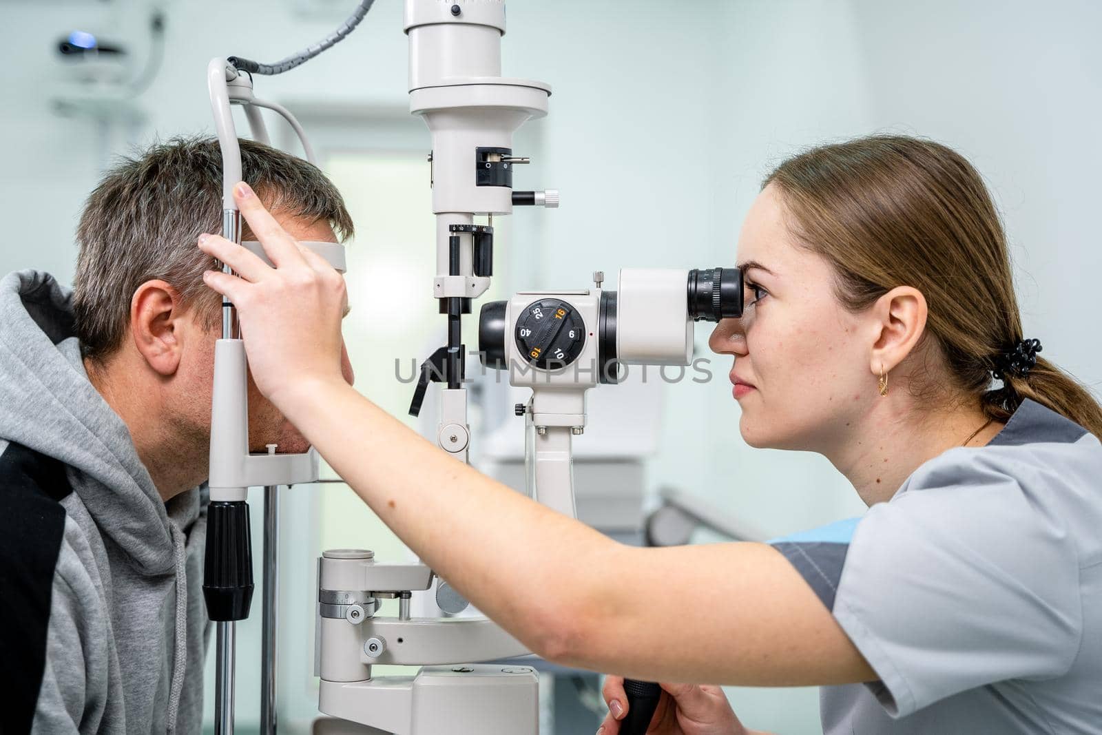 Ophthalmologist and patient testing eyesight. Man doing eye test with optometrist. Ophthalmologist using apparatus for eye examination in clinic. Doctor examining patient doing eyesight measurement.