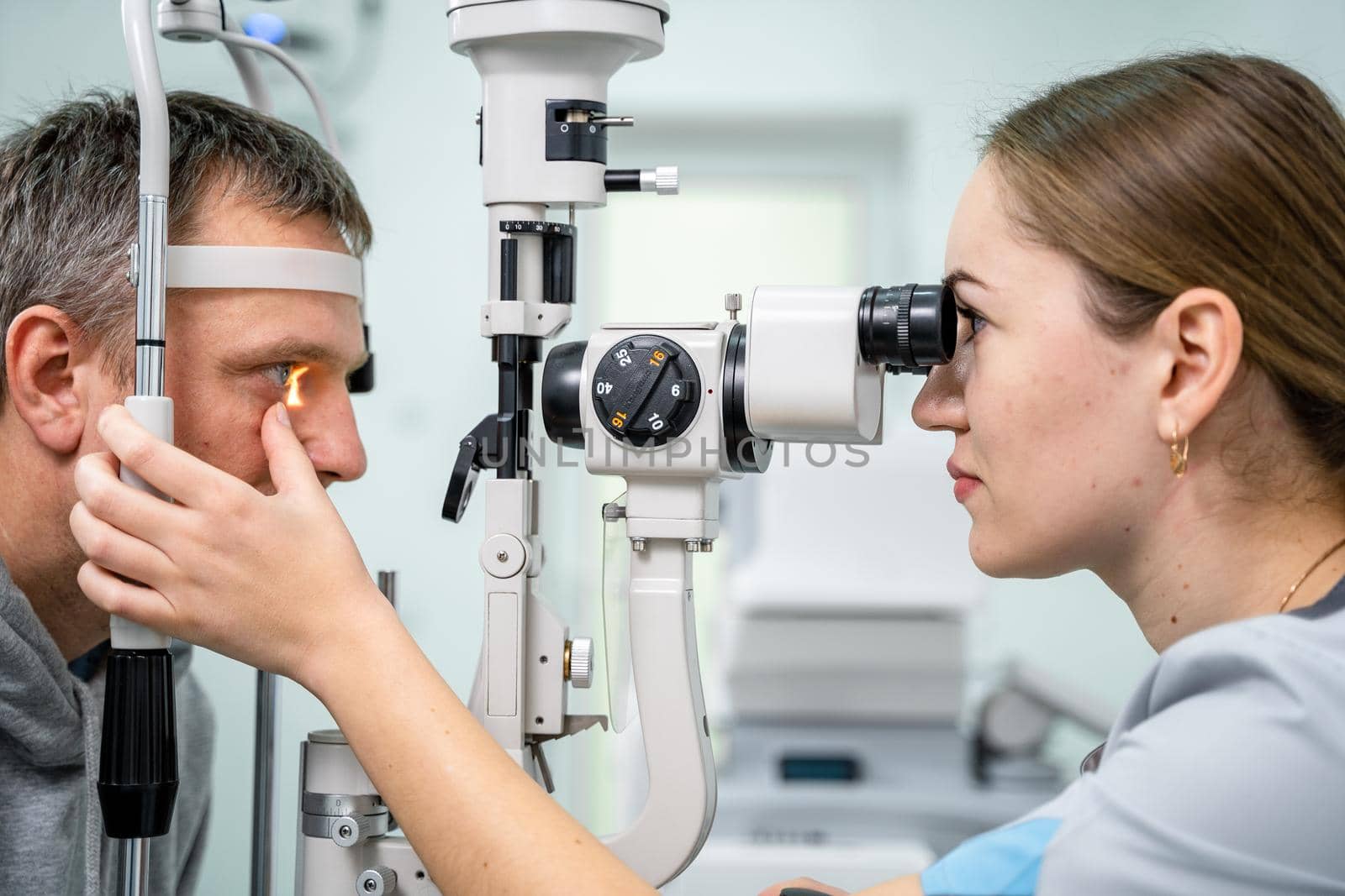 Ophthalmologist and patient testing eyesight. Man doing eye test with optometrist. Ophthalmologist using apparatus for eye examination in clinic. Doctor examining patient doing eyesight measurement by Tomashevska