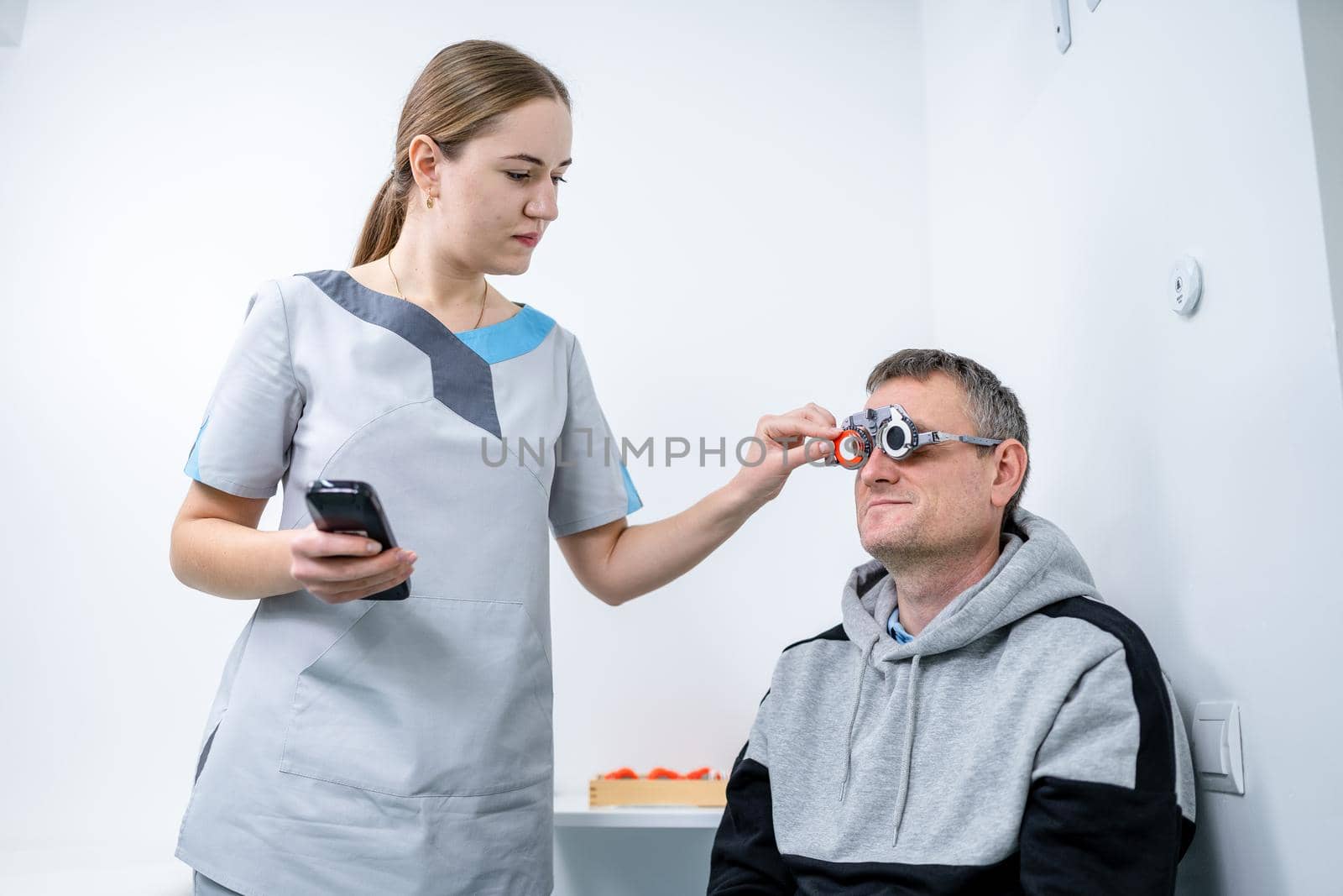 Examining patient vision. Eye exam. Optometrist checking patient eyesight and vision correction. Patient undergoing vision check with special ophthalmic glasses at eye clinic. Selection of eyeglasses by Tomashevska