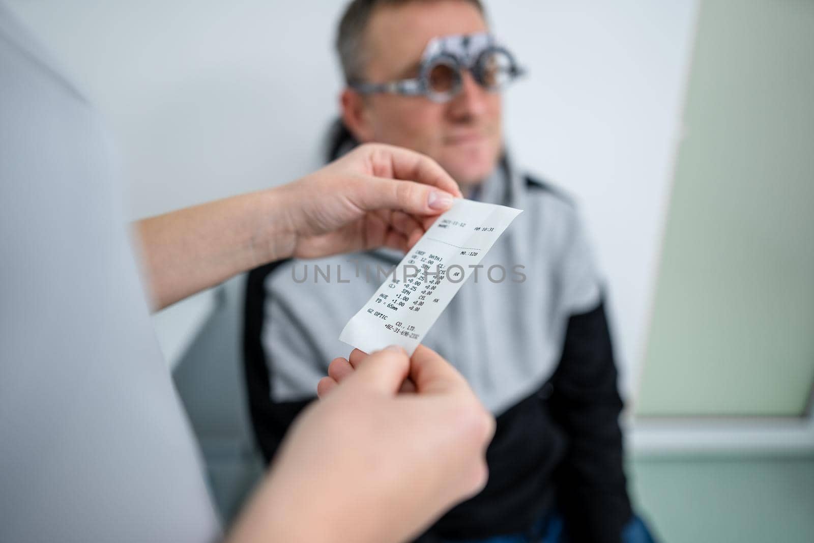 Male patient undergoes an eye test and prescription for eyeglasses in ophthalmology clinic. Optometrist checking patient eyesight and vision correction. Changing lenses on trial frame on patient nose by Tomashevska