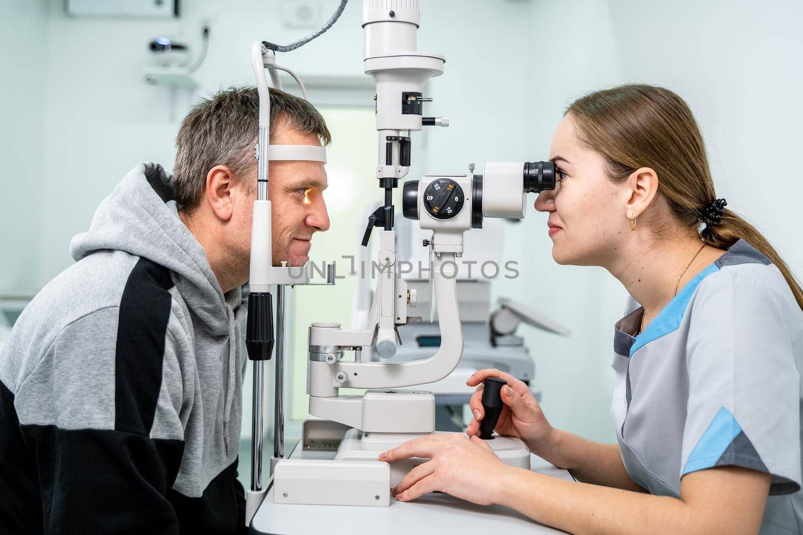 Optometrist examining the eyes of a male patient in a modern ophthalmology clinic. Eye doctor with man patient during an examination in modern clinic. Optometry concept. Eyesight exam in clinic by Tomashevska