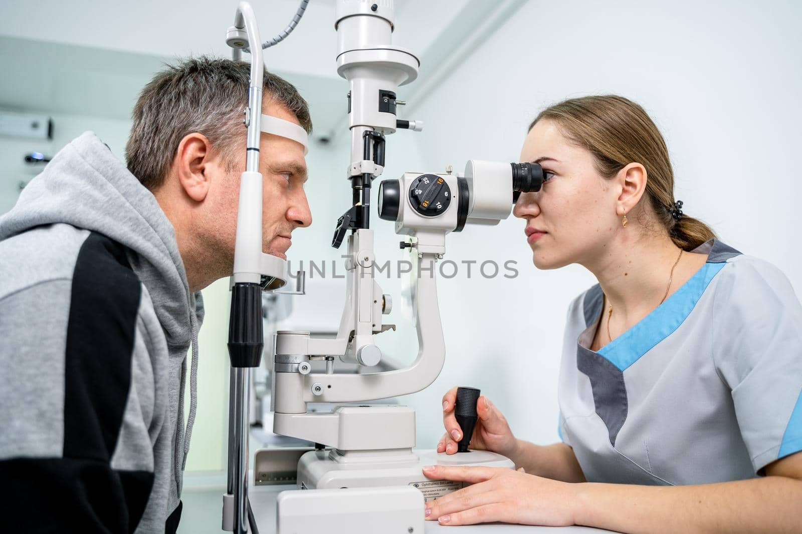 Doctor and patient in ophthalmology clinic. Male patient checking vision with special eye equipment. Optometry concept. Man visiting optician. Patient at slit lamp of optician or optometrist by Tomashevska