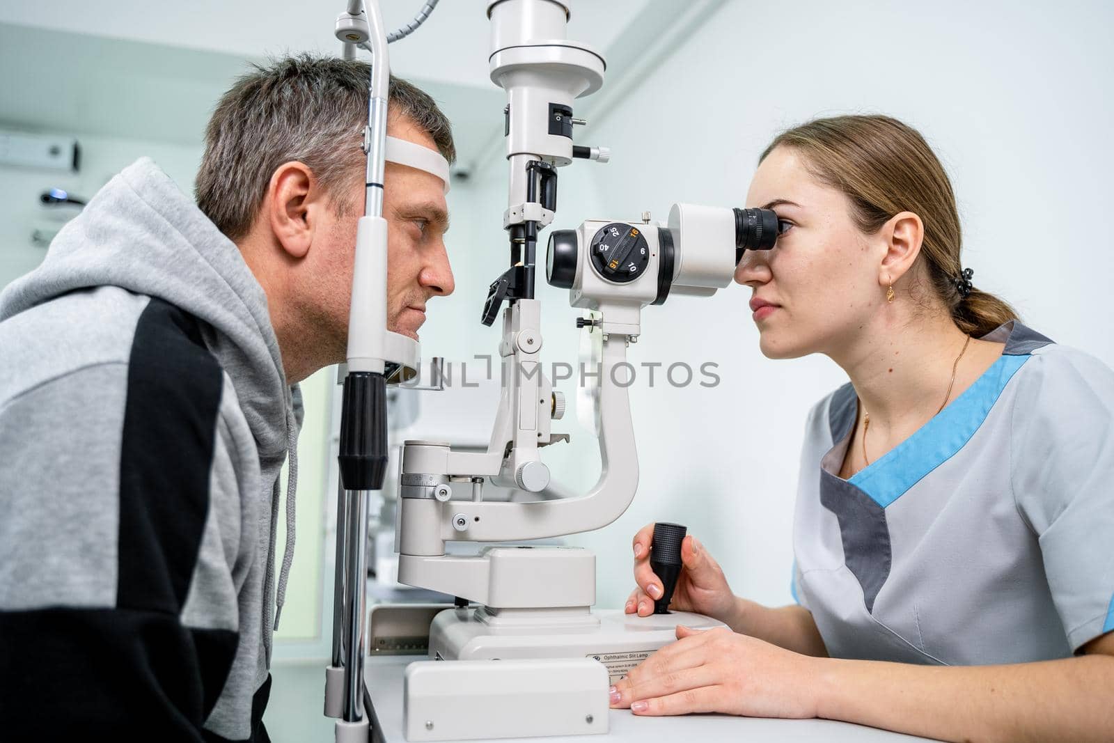 Ophthalmologist and patient testing eyesight. Man doing eye test with optometrist. Ophthalmologist using apparatus for eye examination in clinic. Doctor examining patient doing eyesight measurement by Tomashevska