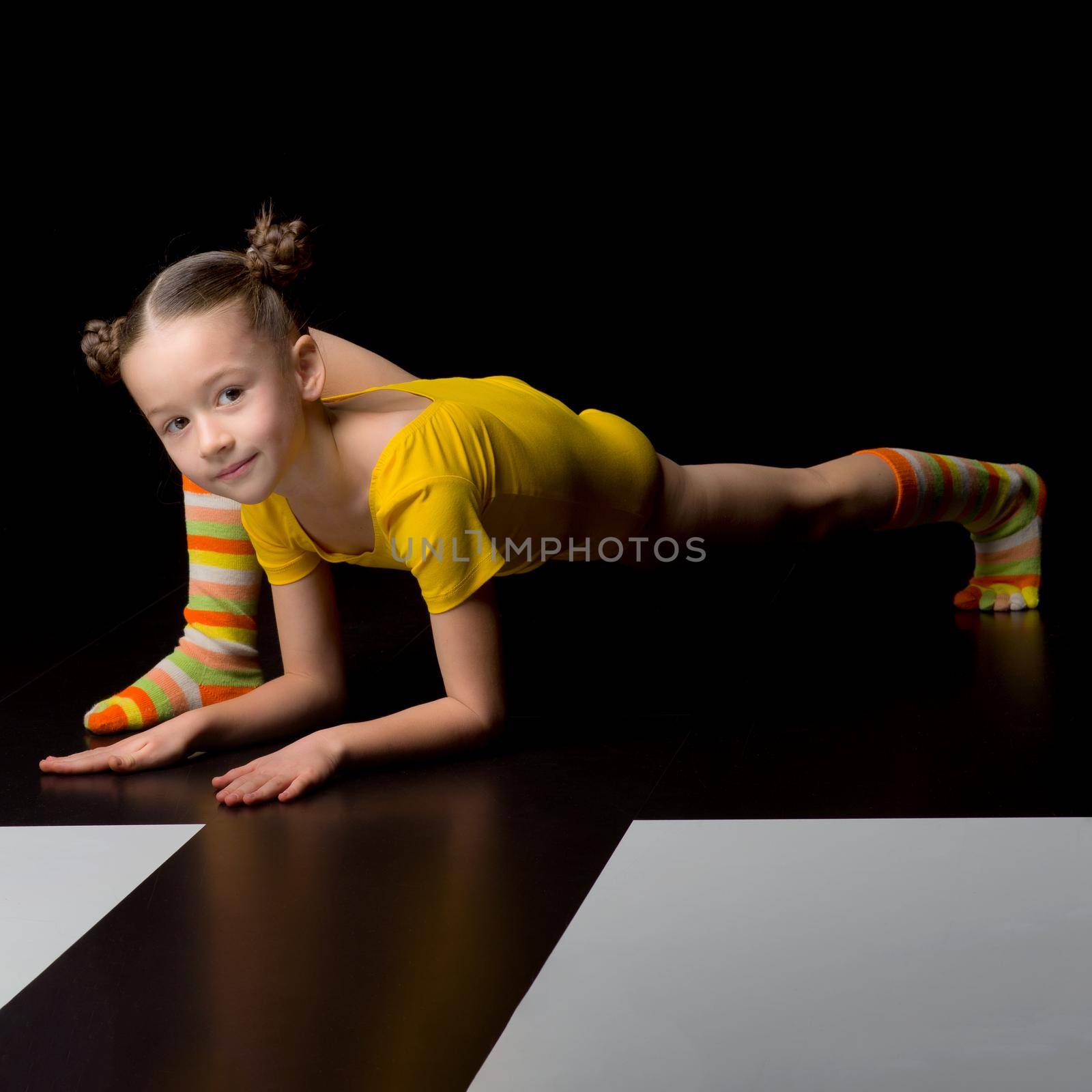 Cute flexible little girl doing elbow plank exercise by kolesnikov_studio