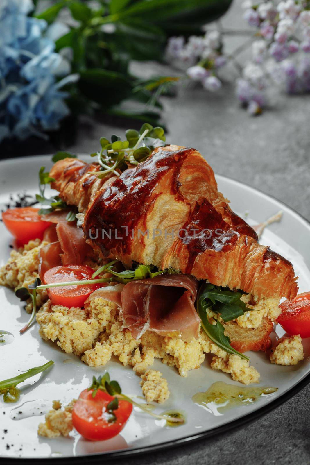 Delicious croissant sandwich with ham, cheese and scrambled eggs on plate served by UcheaD