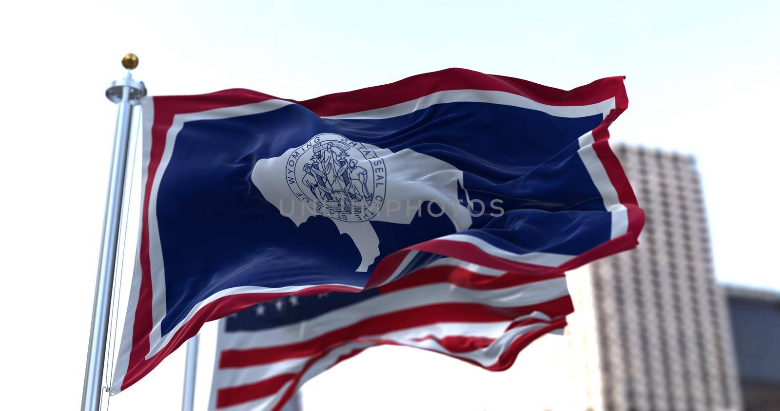 the flag of the US state of Wyoming waving in the wind with the American flag blurred in the background. Wyoming was admitted to the Union on July 10, 1890 as 44th state