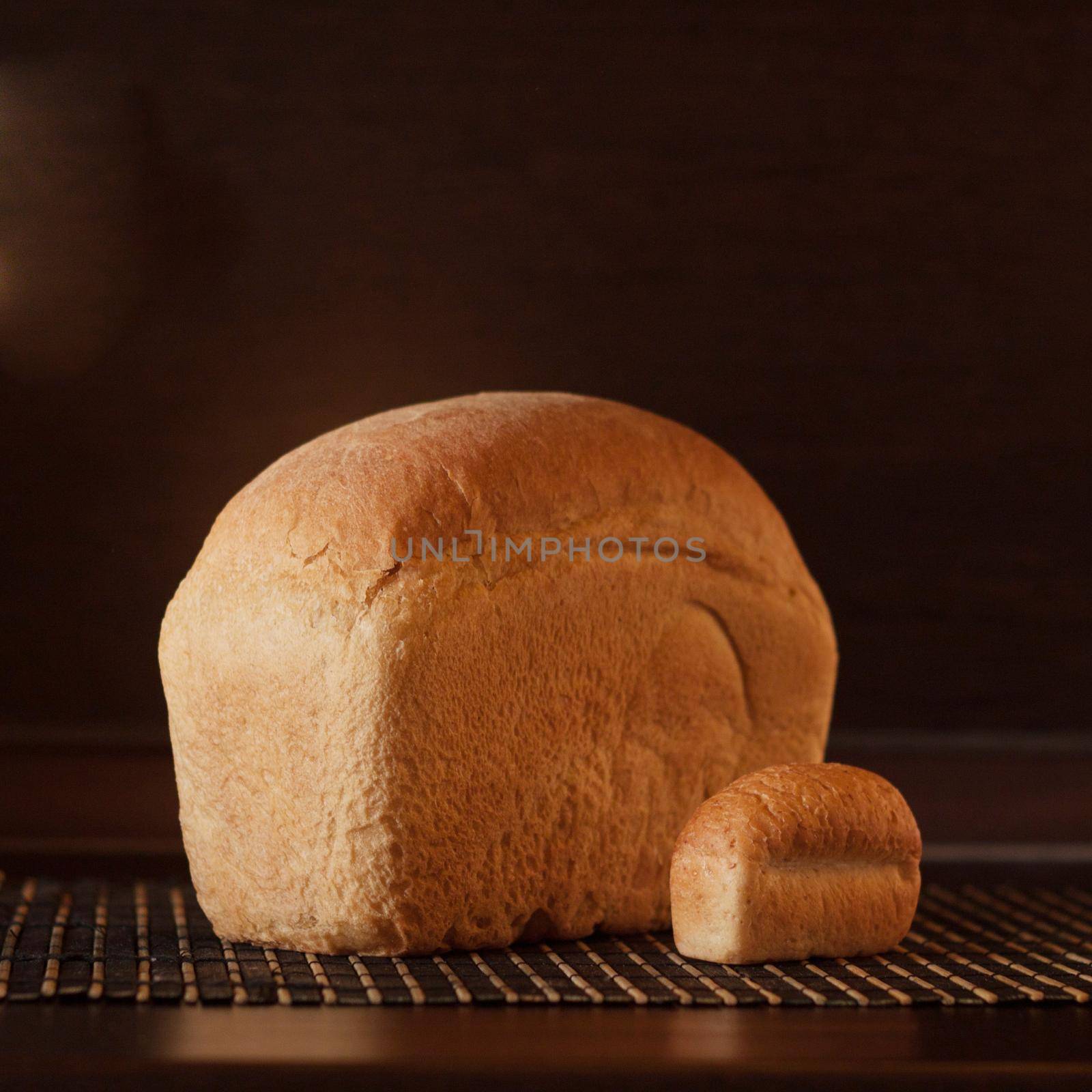 big and small loaf of bread laying on the table on black background by dreamloud