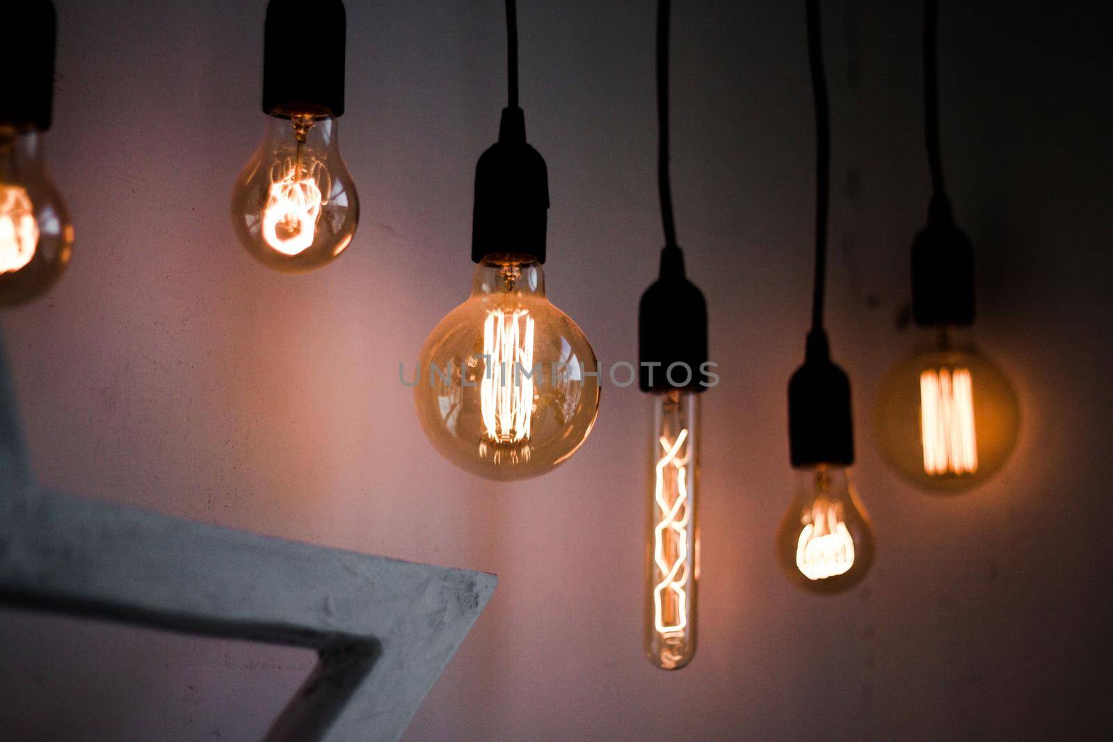 Hanging edison light bulbs on black strings. Glowing vintage electric bulbs