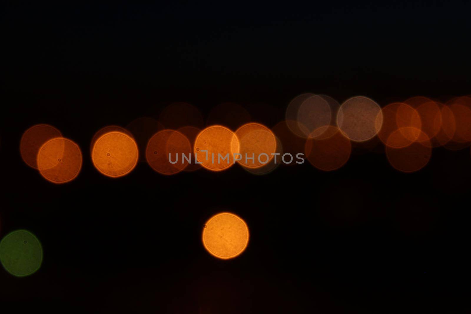 Round orange bokeh lights on black background. Defocused city lights by dreamloud