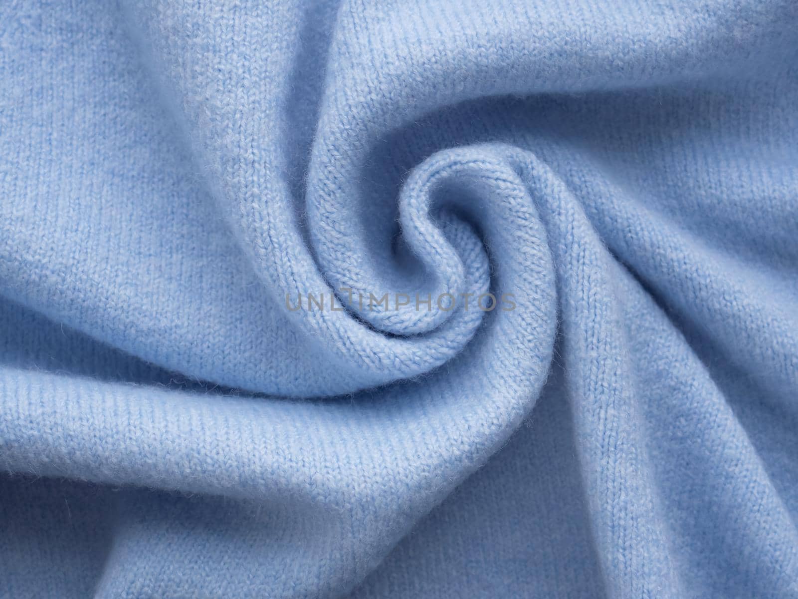 Comfortable style cloth. Simple knitted blue cashmere sweater. Pastel blue backdrop with curves, luxury fashion. Smooth elegant wrinkled fabric background. Abstract crumpled texture. Soft focus