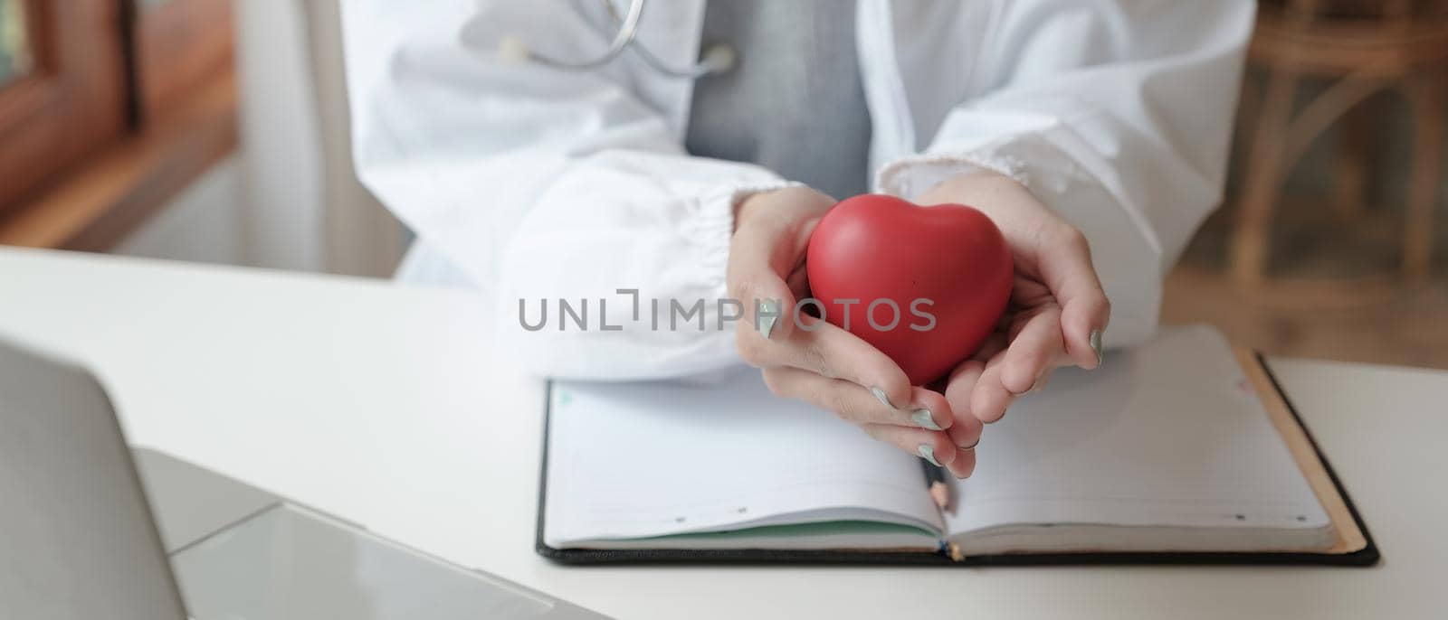 Crop shot of female doctor with stethoscope holding heart model - Cardiologist healthcare concept.