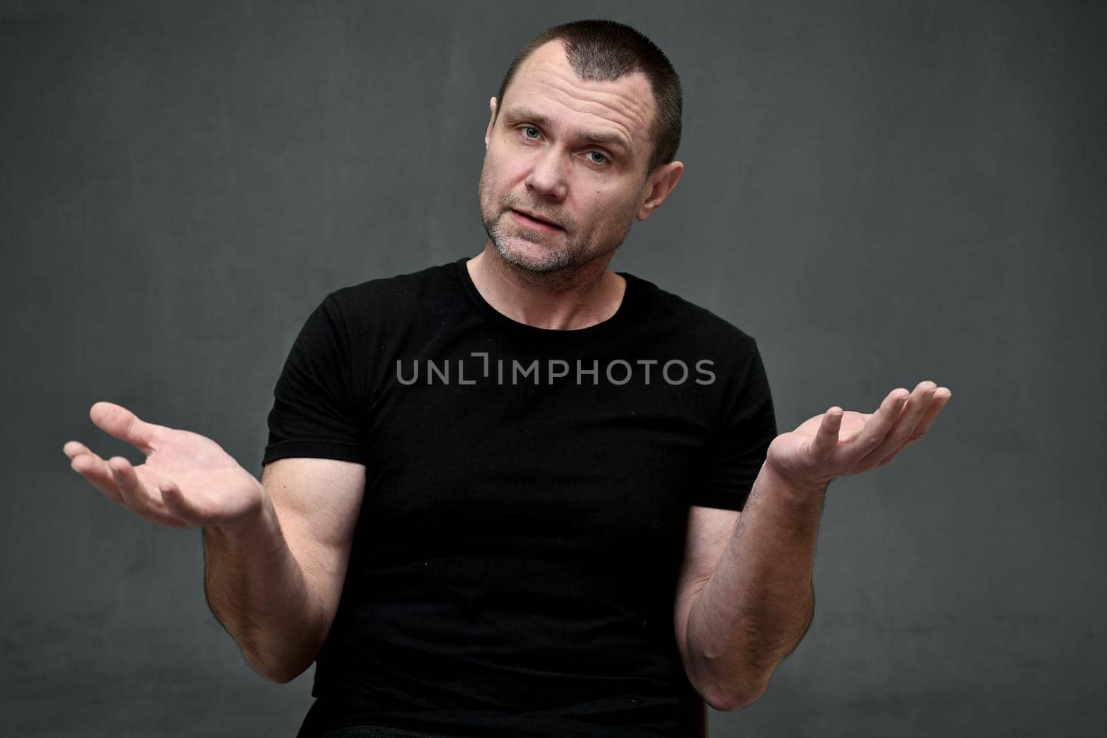 Portrait of an adult man talking directly to the camera on a gray background