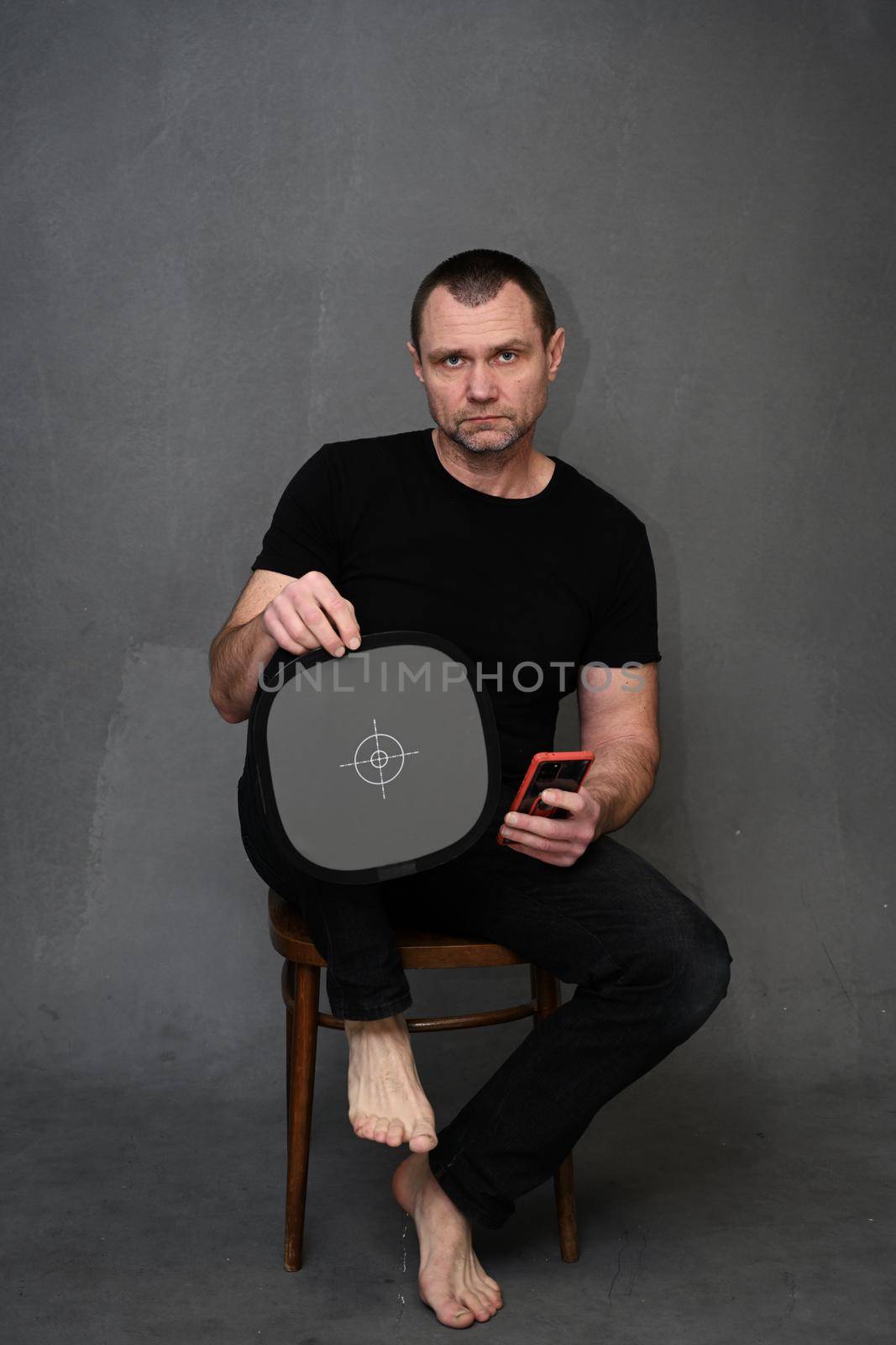 portrait of a man with a smartphone in his hand and a target looking at the camera