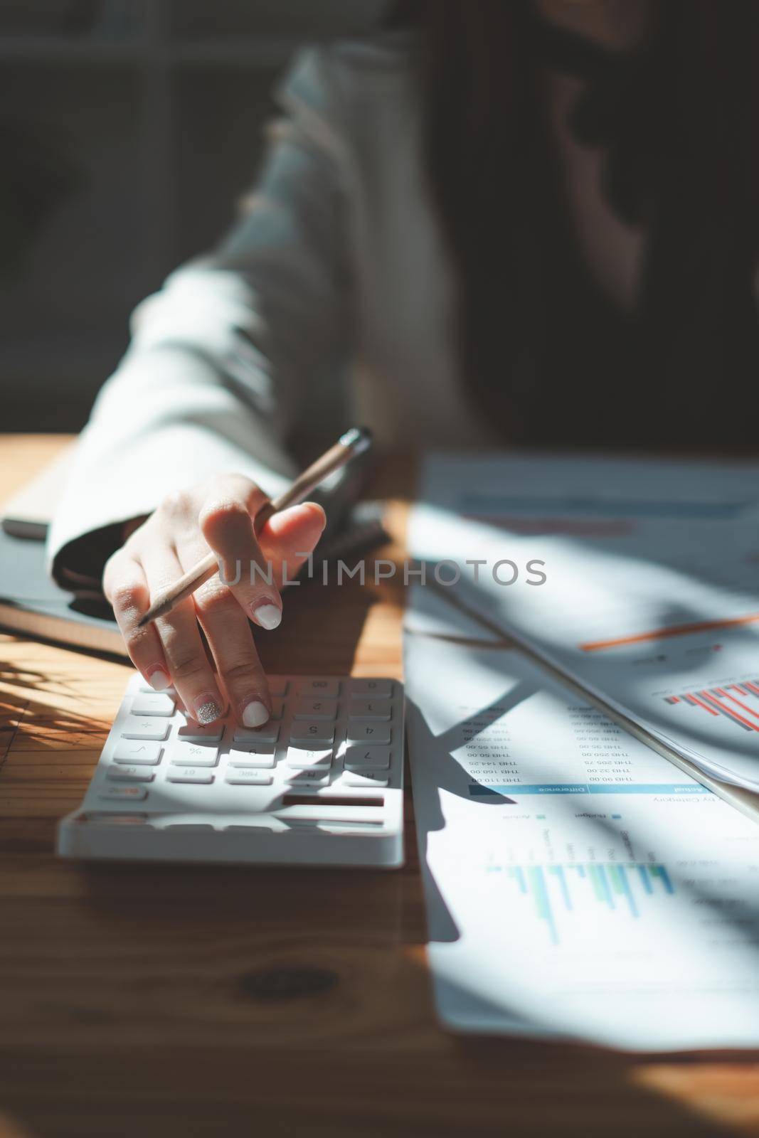 Close up Business woman using calculator for audit finance budget on wooden desk in office, tax, accounting, statistics and analytic research concept. by itchaznong