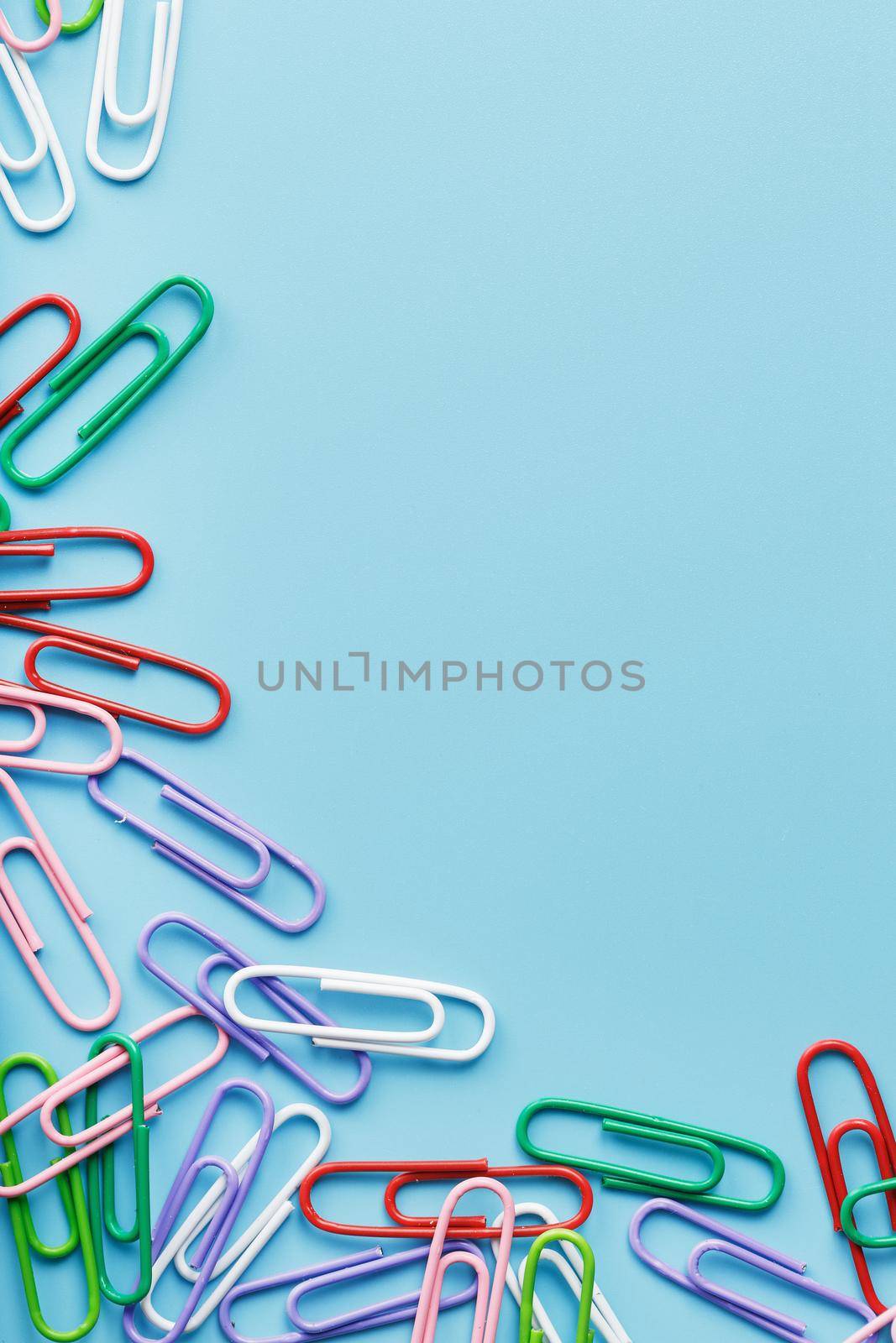 Multicolored paper clips on a blue background. Free space