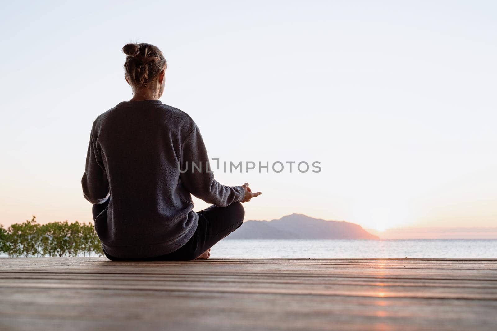 Health and wellness. Young healthy woman practicing yoga meditating on the beach at sunset