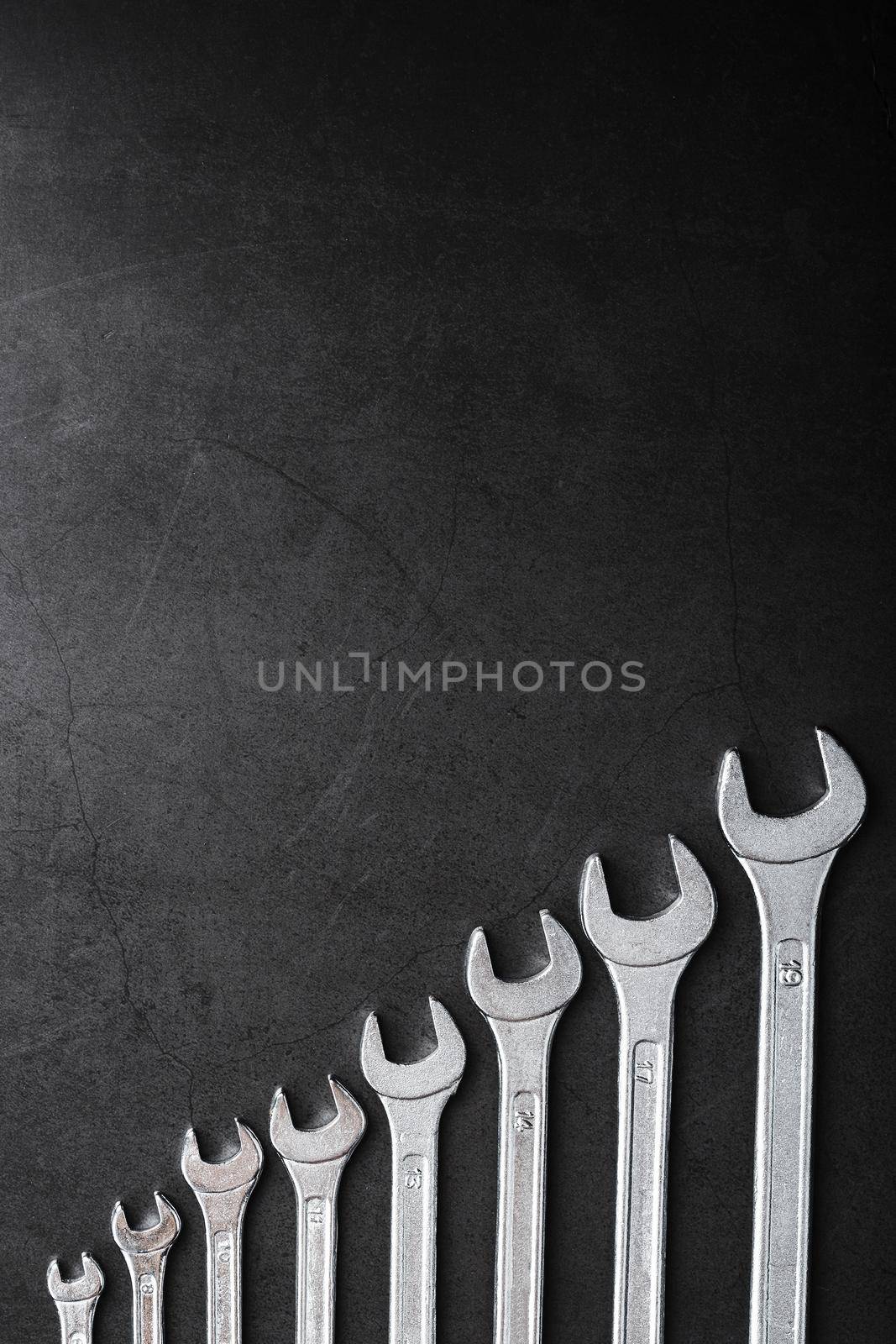 Tool wrenches in a row on a black background with free space. Top view