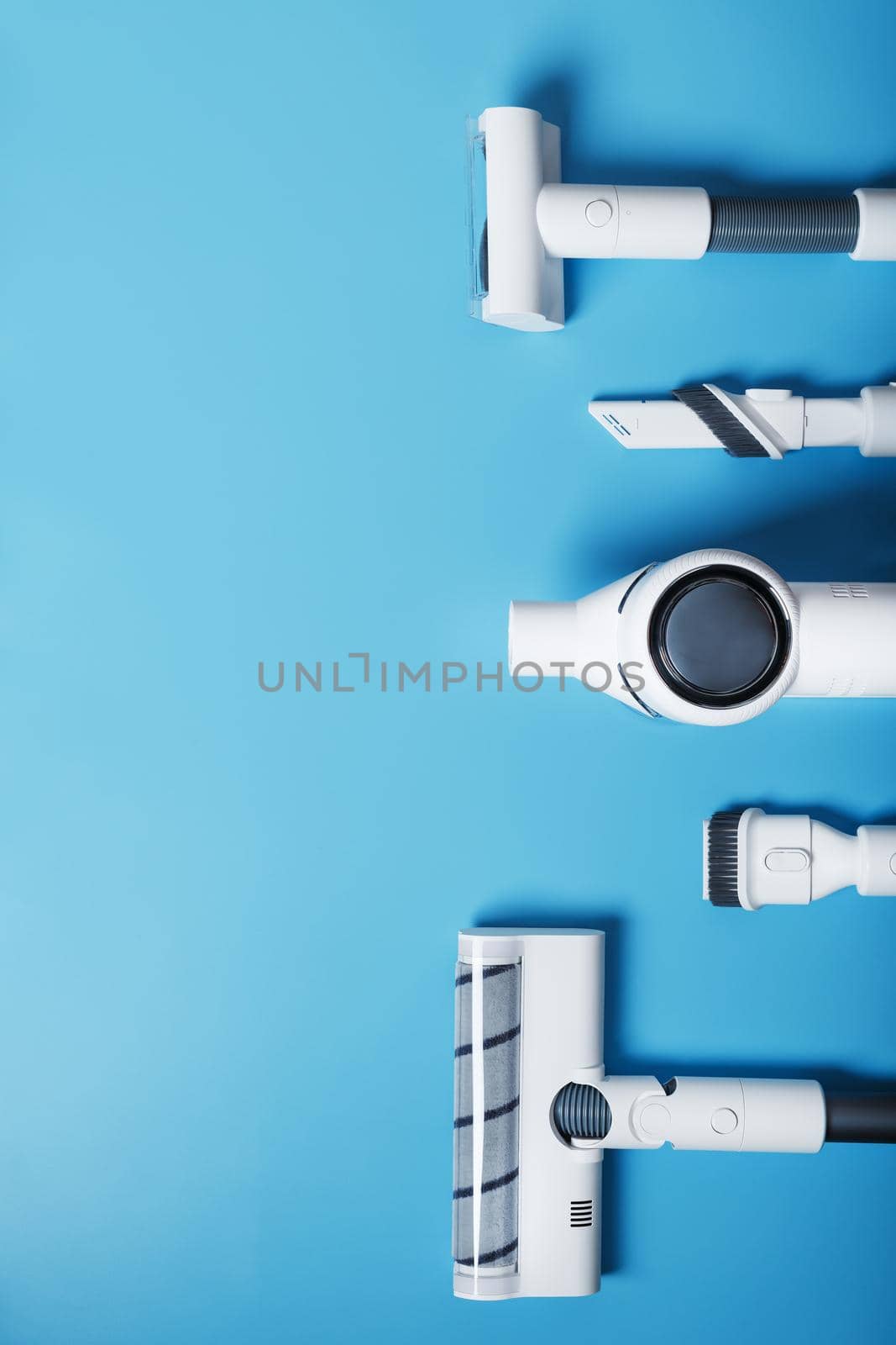 Composition of a set of elements of a wireless white vacuum cleaner on a blue background. Top view by AlexGrec
