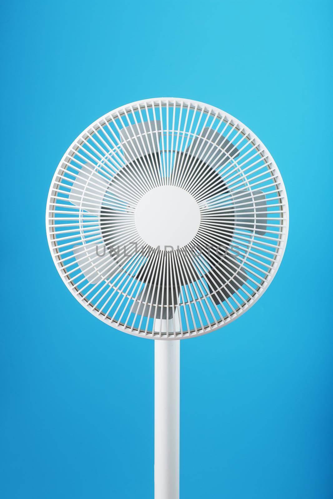 The grille and blades of the electric fan are white on a blue background. Minimalistic style, close-up