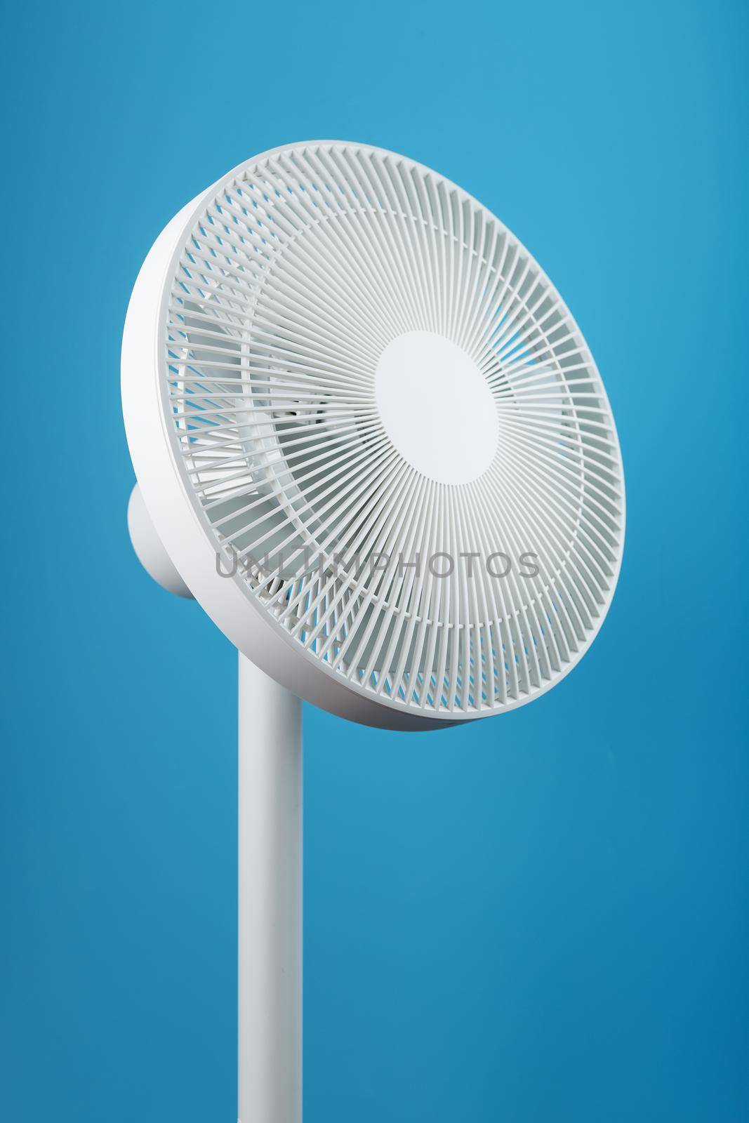 A high-tech white electric fan with a modern design for cooling the room on a blue background by AlexGrec