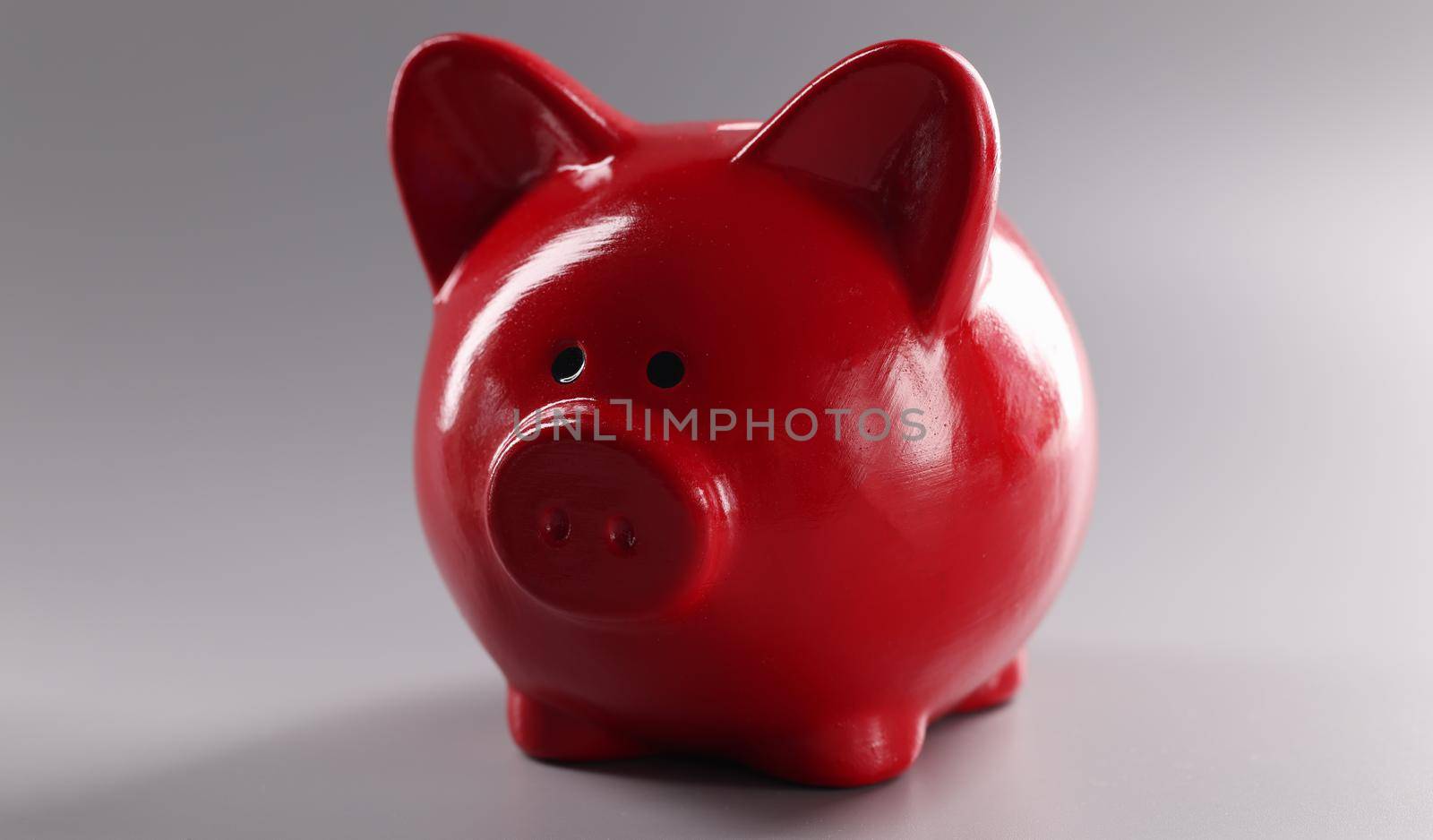 Closeup of red piggy banks for coins on gray background. Cash savings concept
