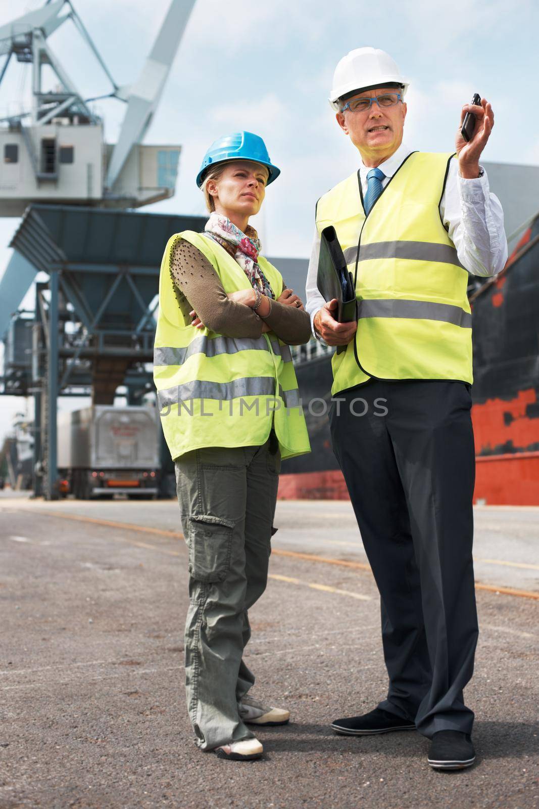 Effective communication among co-workers is vital. Two engineers discussing planning on a site while in the shipyard. by YuriArcurs