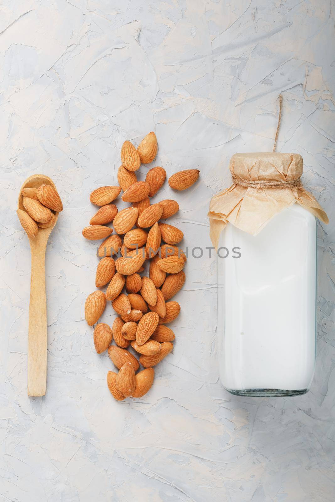 Vegan Milk from a handful of organic almond seeds in a bottle on a light background. by AlexGrec
