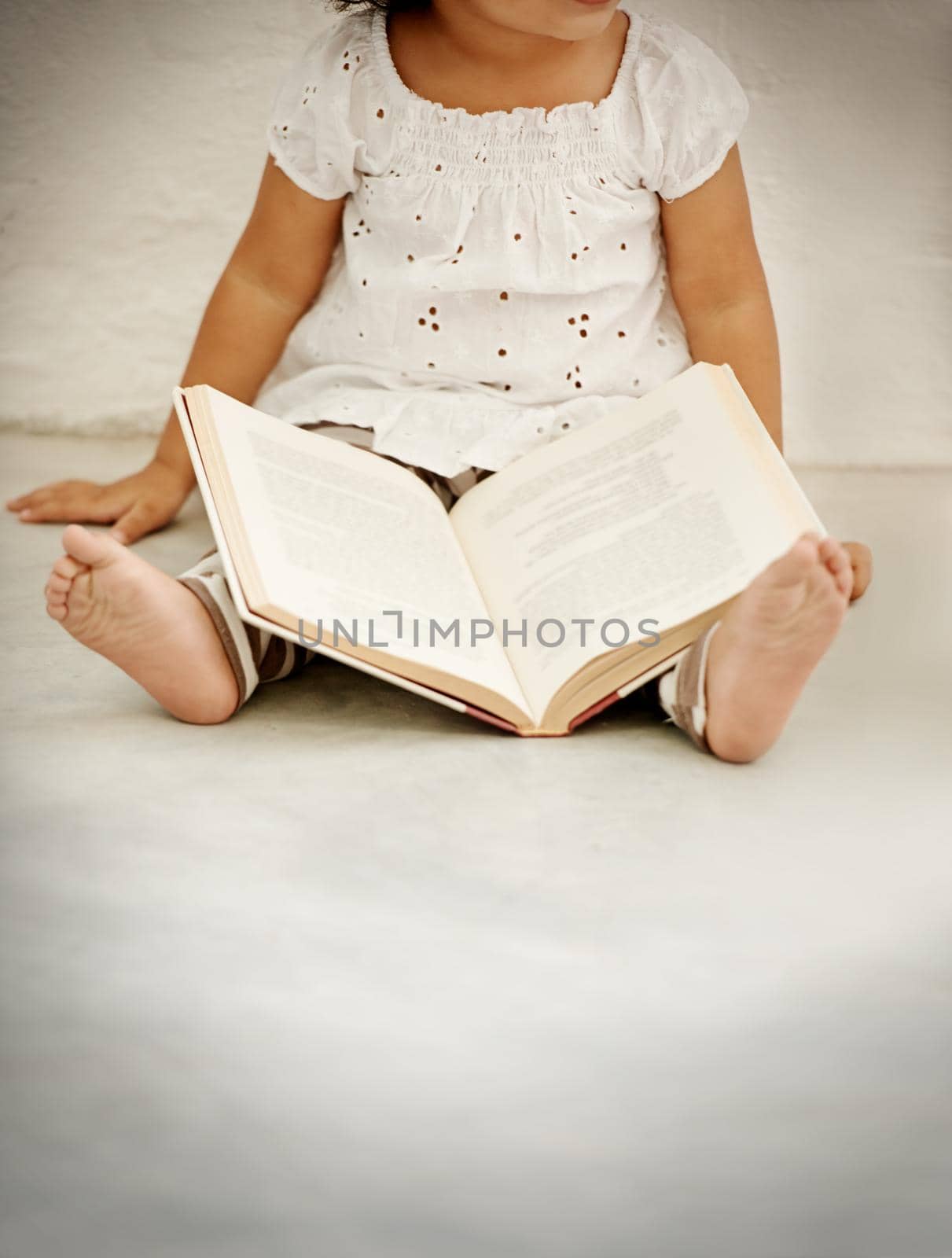 Catching up on my reading. A little girl reading a book. by YuriArcurs