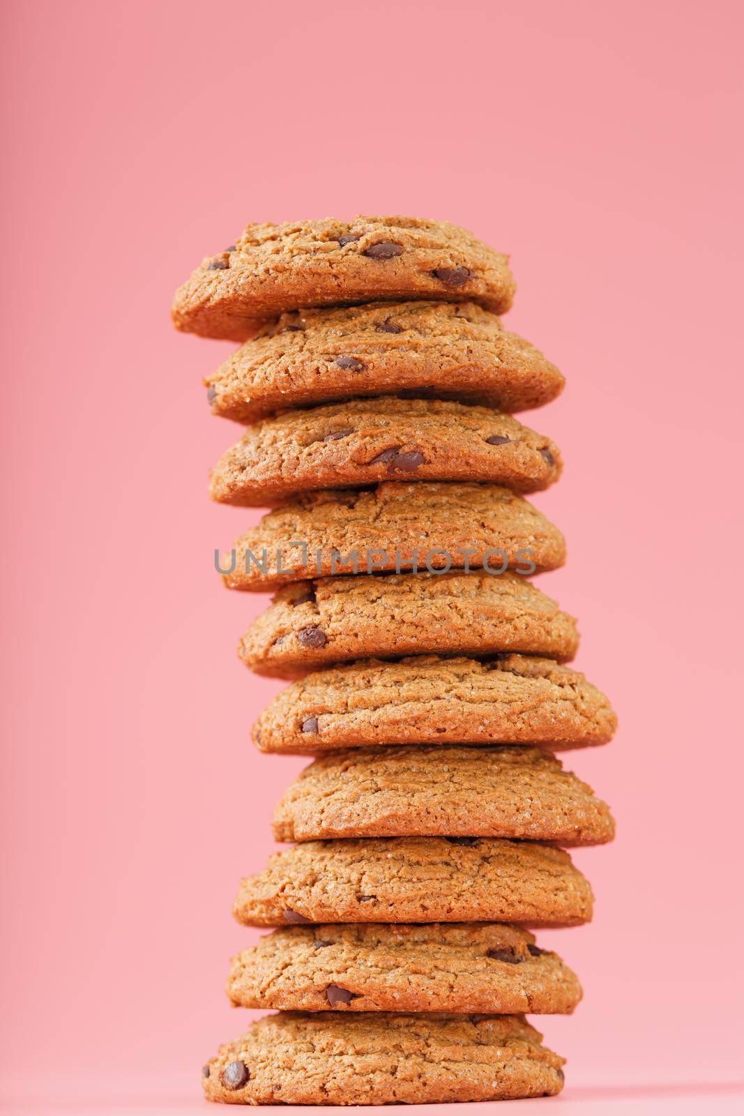 Oatmeal cookies with chocolate are stacked on a pink background. Free space