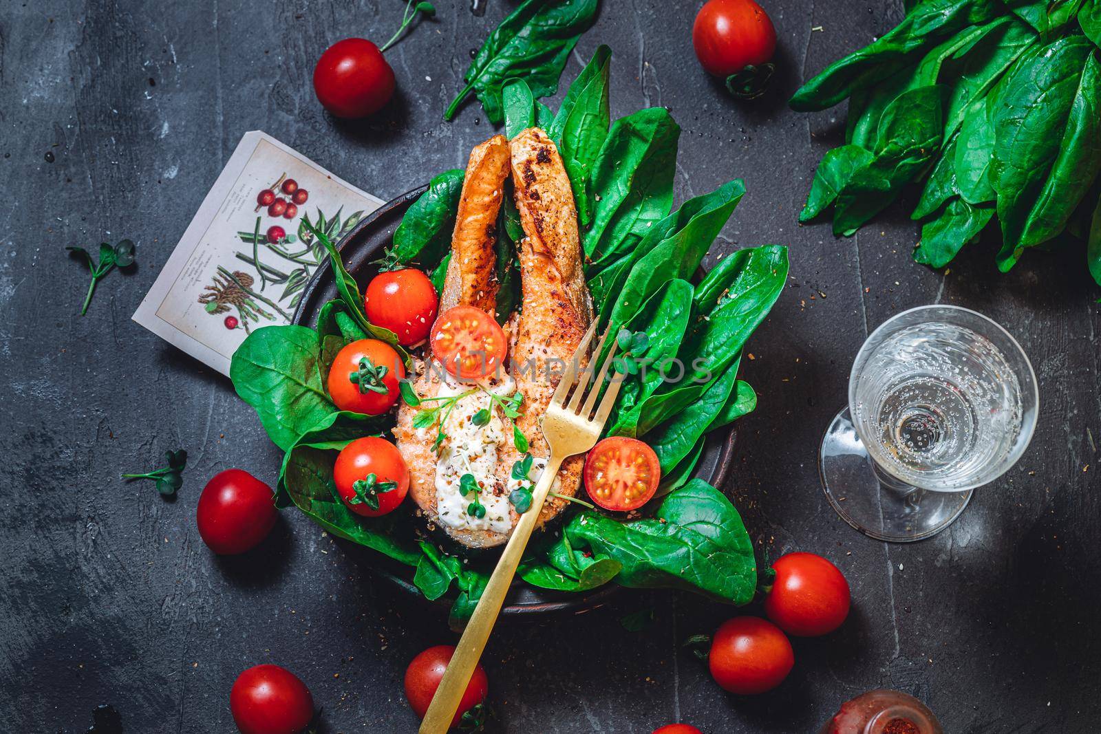 A plate with fresh green raw spinach and fried wild salmon, tomatoes and cream cheese sauce High quality photo