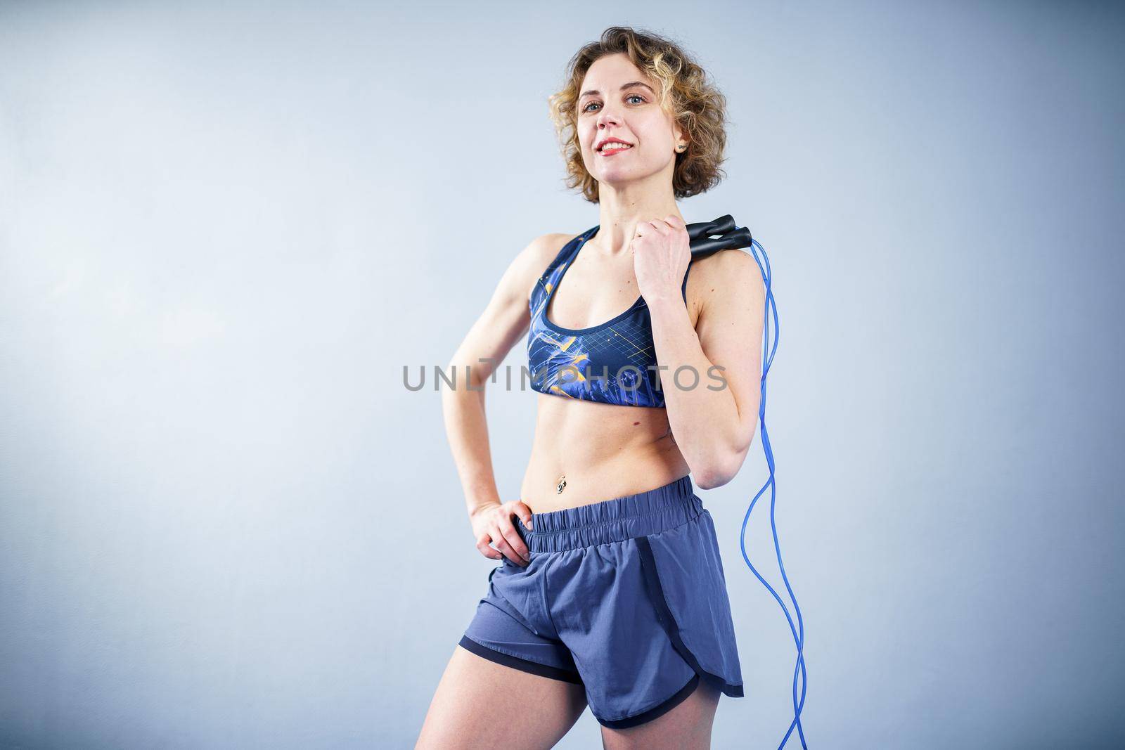 Fit woman with jump rope posing in the gym. Sport exercises healthy lifestyle concept. Sporty happy woman with skipping rope posing to the camera. Active lifestyle concept. Healthy lifestyle by Tomashevska