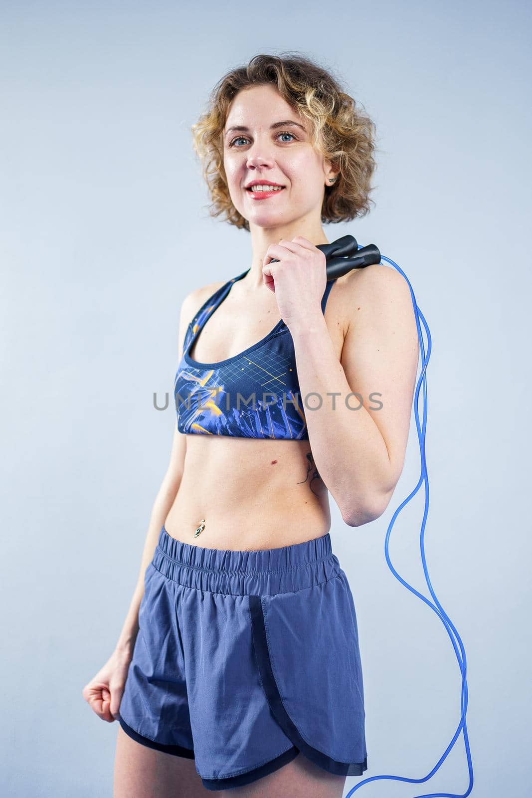 Fit woman with jump rope posing in the gym. Sport exercises healthy lifestyle concept. Sporty happy woman with skipping rope posing to the camera. Active lifestyle concept. Healthy lifestyle by Tomashevska