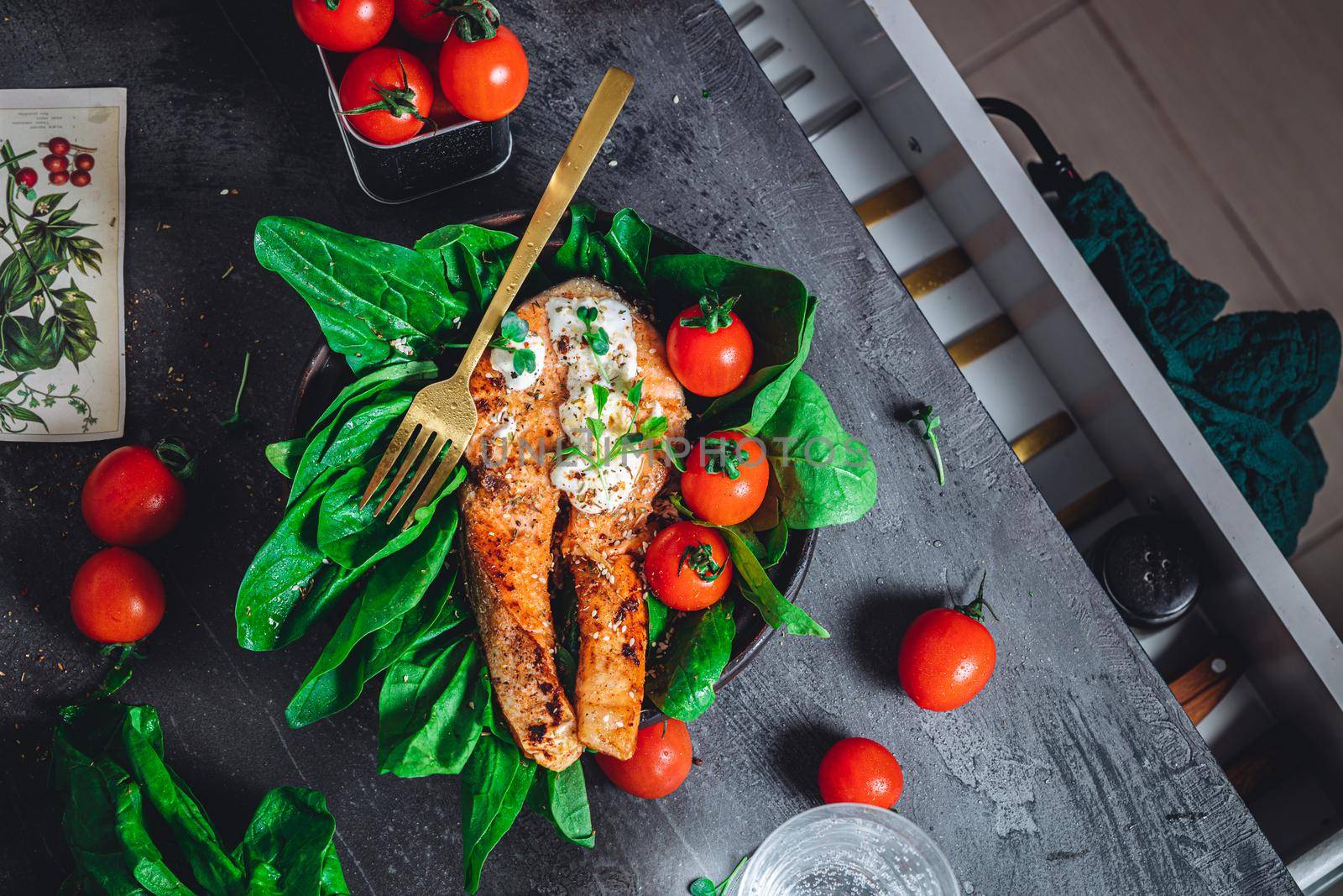 A plate with fresh green raw spinach and fried wild salmon, tomatoes and cream cheese sauce High quality photo